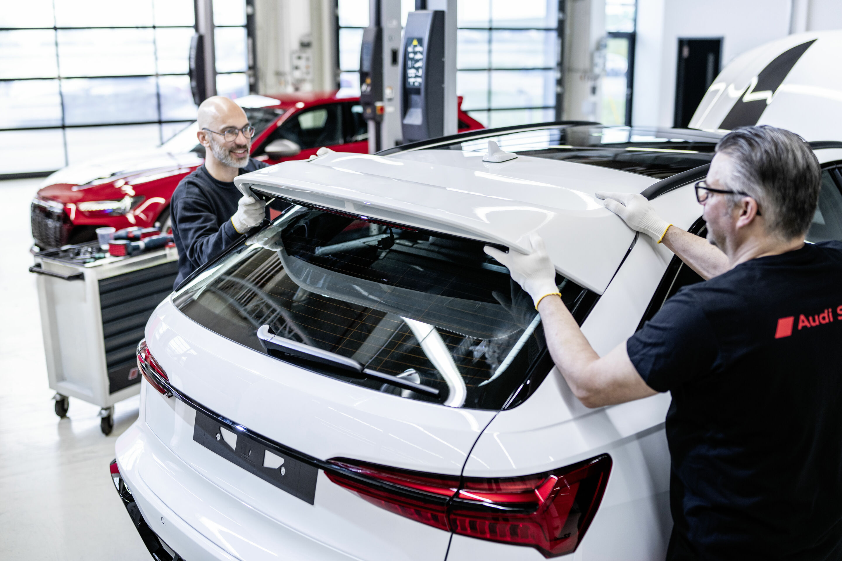 Audi RS 6 Avant GT - Zwei der insgesamt fünf Mitarbeiter_innen der Böllinger Höfe vervollständigen die Montage des neuen Audi RS 6 Avant GT von Hand. Ein besonderes Highlight: der aus dem Motorsport inspirierte Doppelflügel.