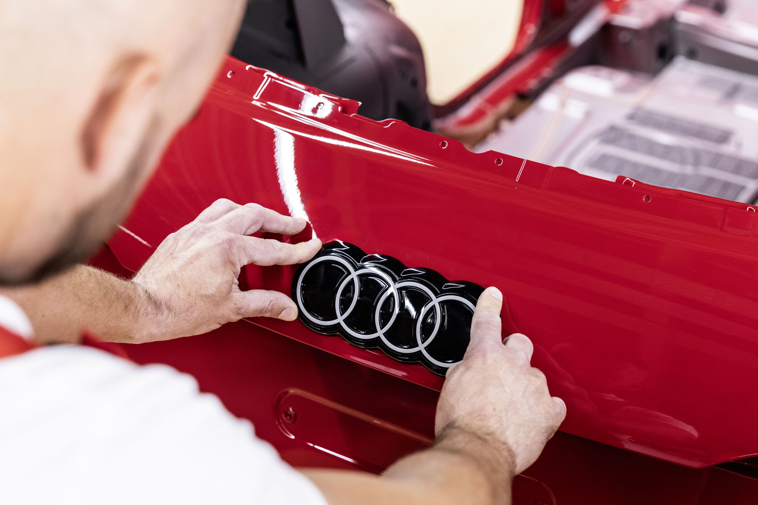 Audi Q3 SUV - Der Audi Q3 wird bei Audi Hungaria in Győr gefertigt. Im Bild: Montage der Audi Ringe, Farbe: Progressivrot metallic
