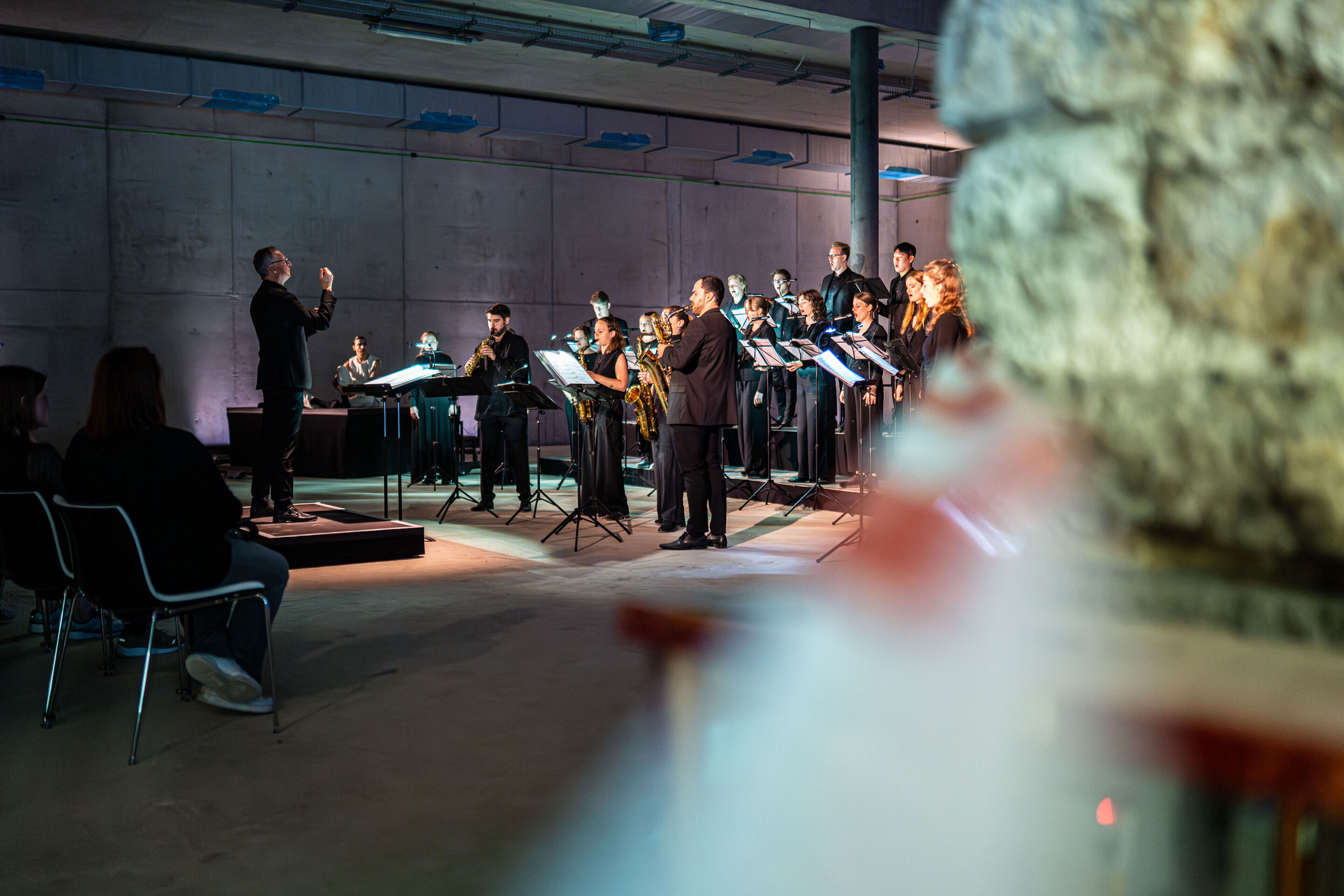 “Lux!”: Theatrical concert at the construction site of the MCAD; Arcis Saxophone Quartet, vocal ensemble LauschWerk - The side view shows conductor Martin Steidler during the staged concert “Lux!” at the construction site of the new Museum of Concrete...