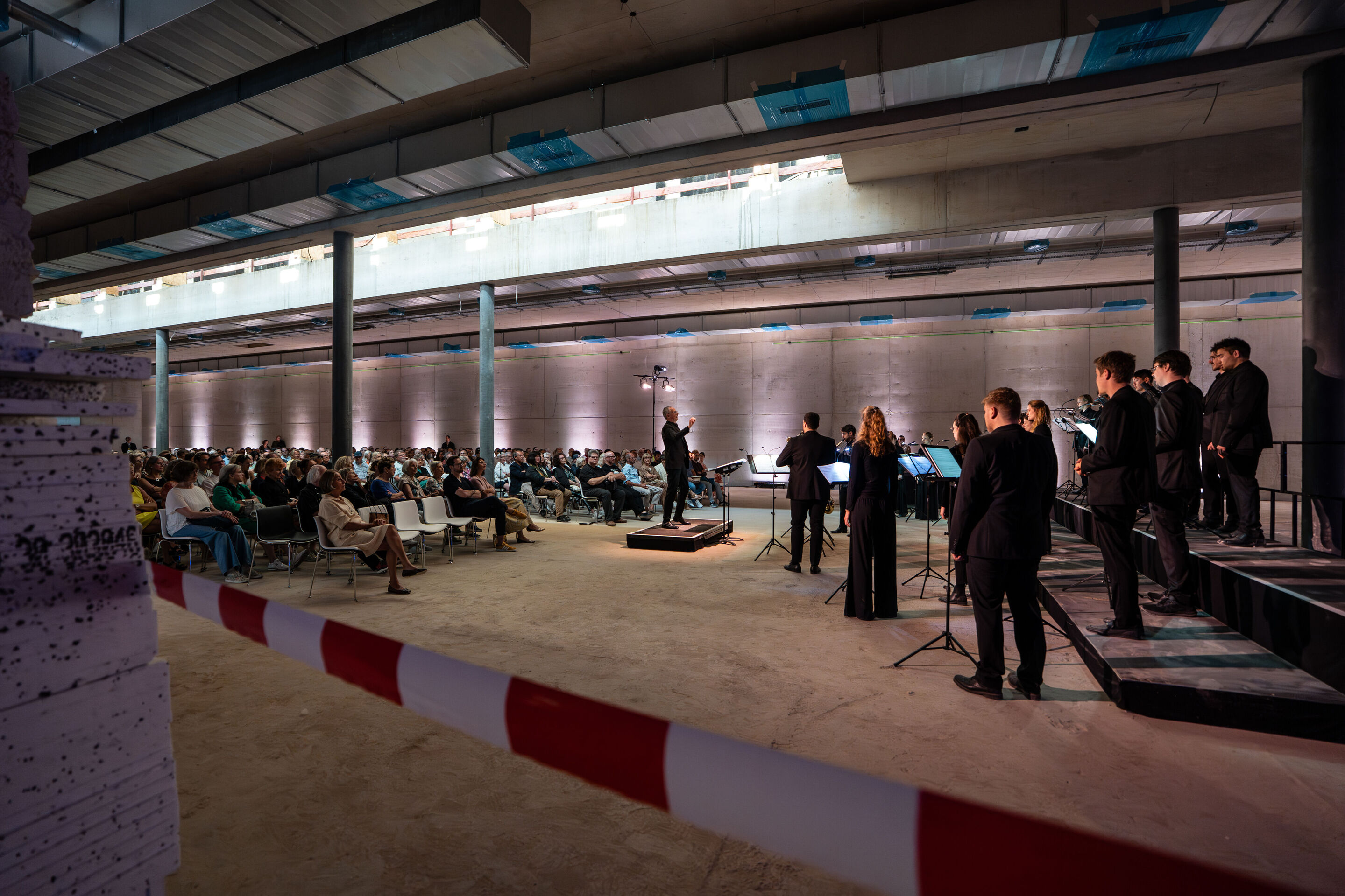 “Lux!”: Theatrical concert at the construction site of the MCAD; Arcis Saxophone Quartet, vocal ensemble LauschWerk - On the construction site of the new Museum of Concrete Art and Design Ingolstadt, the side view of the staged concert “Lux!” shows conductor...