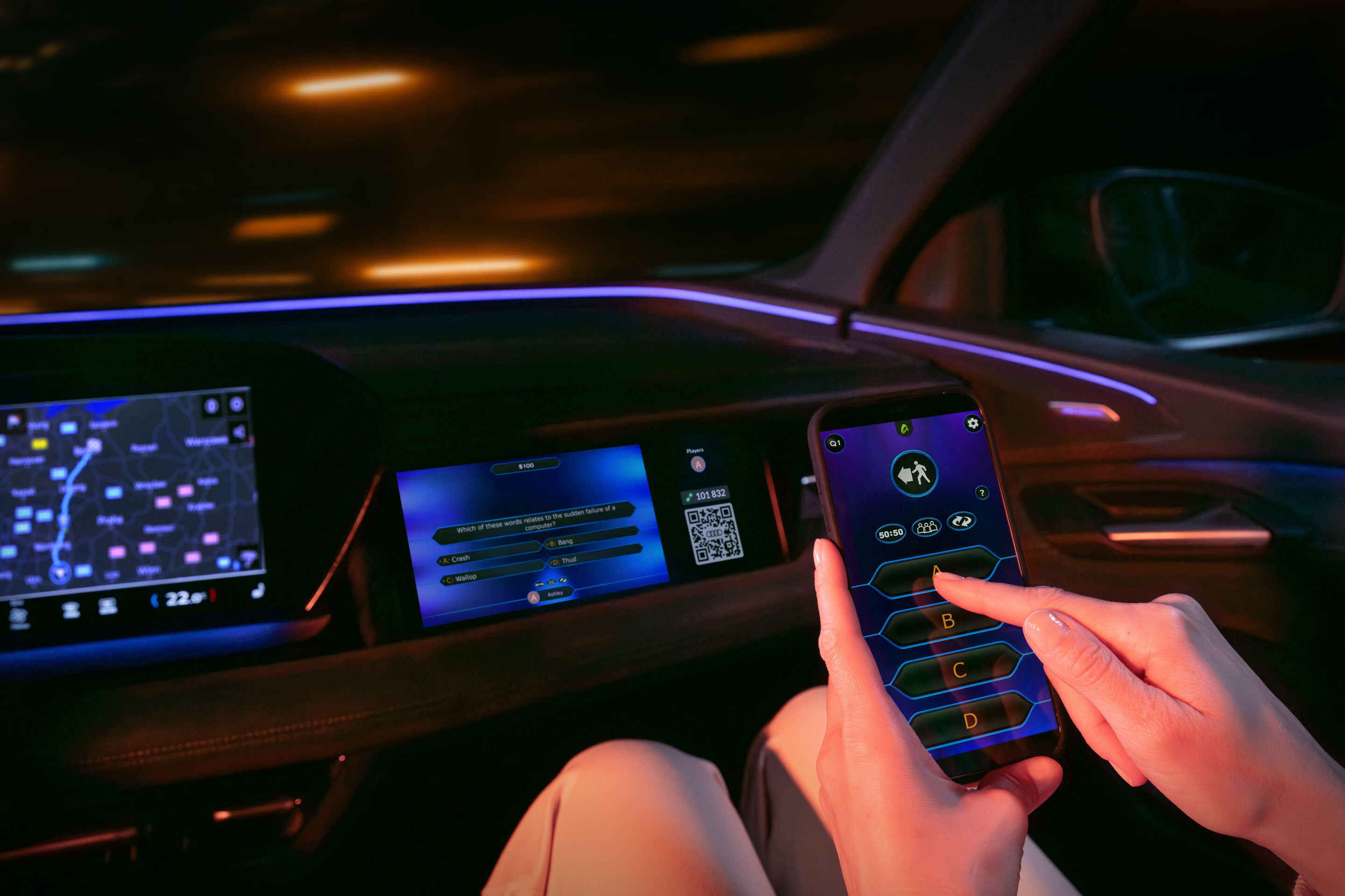 Gaming fun on the go: Audi integrates AirConsole - The AirConsole gaming platform app and the game Who Wants to Be a Millionaire? run on the front passenger display in an Audi. A person is holding a smartphone in front of the display. They use the smartphone...