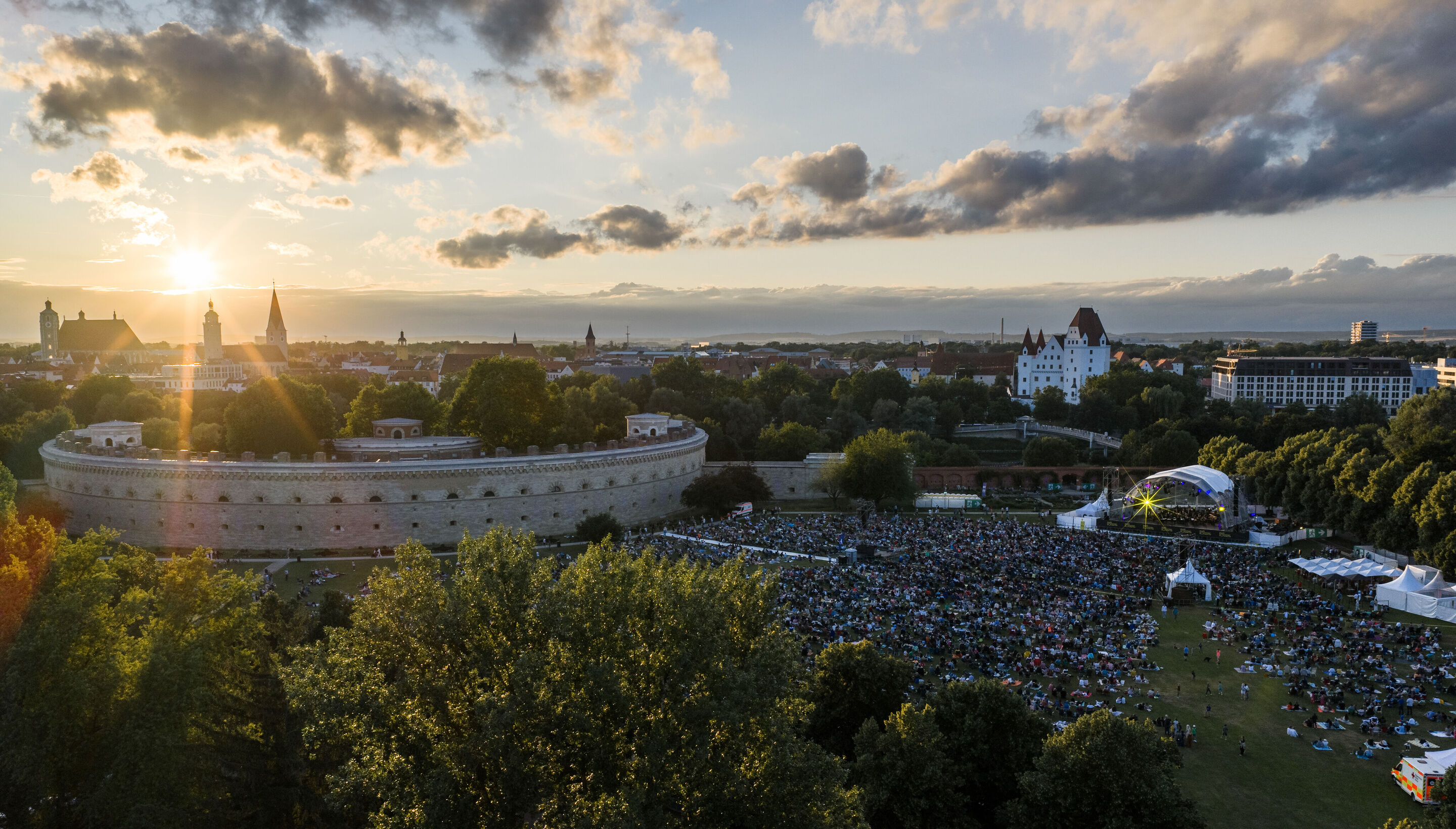 Klassik Open Air – Musical-Highlights mit der Audi Bläserphilharmonie - Blick aus der Vogelperspektive auf das Klassik Open Air mit der Audi Bläserphilharmonie im Rahmen der Audi Sommerkonzerte im Klenzepark in Ingolstadt; auf der rechten Seite das Publikum...