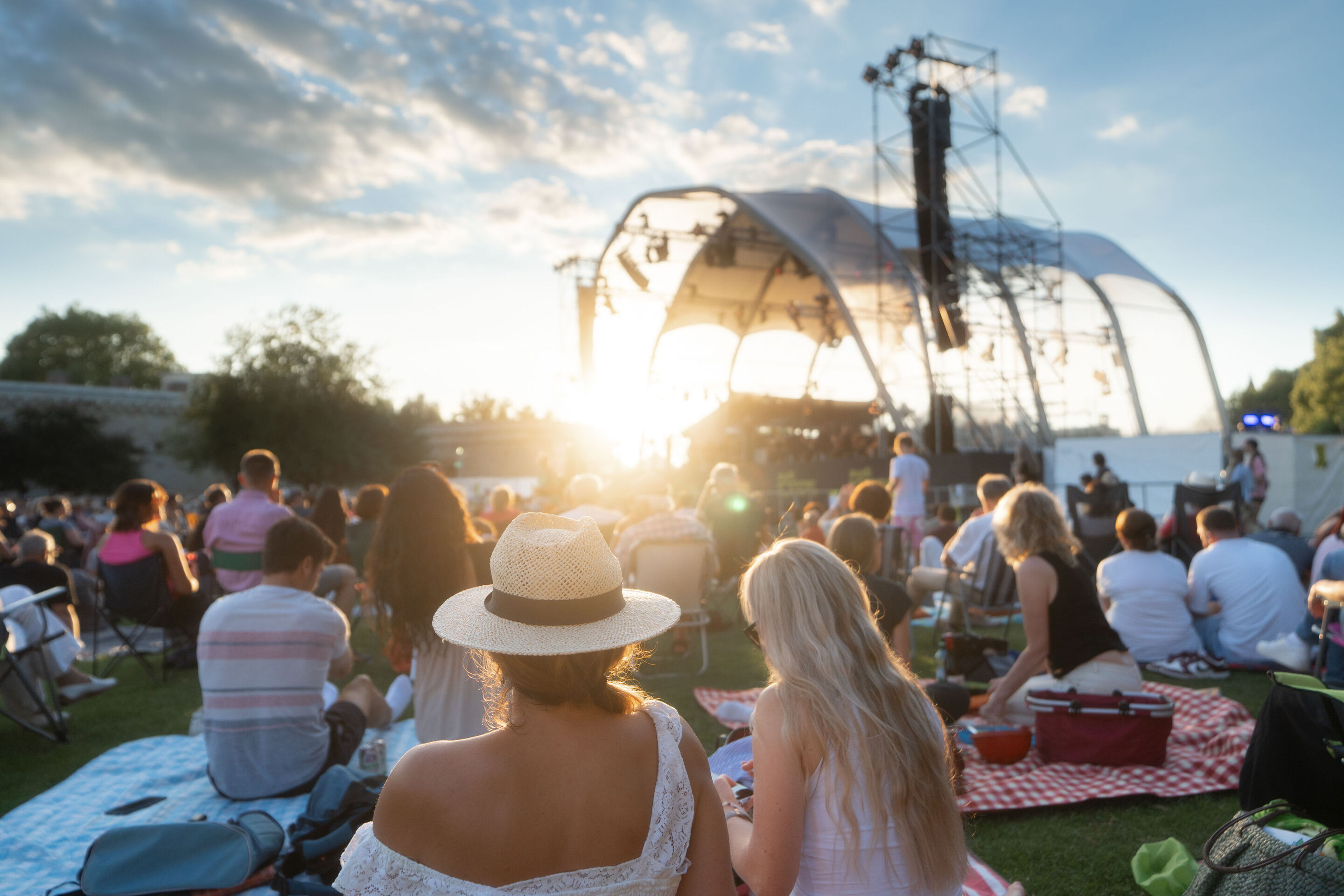 Classic Open Air – German–Italian opera night with the Georgian Chamber Orchestra Ingolstadt - People sit on chairs and blankets on the grass in the early evening in front of the stage in Klenzepark, where the Classic Open Air event featuring the Georgian...