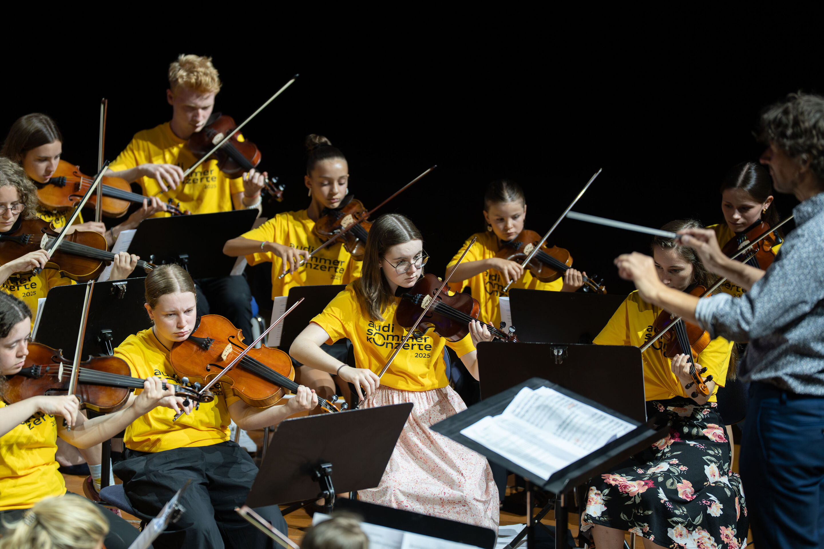 Öffentlicher Workshop mit Schülerinnen und Schülern der Region und dem Aurora Orchestra - Auf der Bühne des Festsaals Ingolstadt musizieren Schülerinnen und Schüler aus Ingolstädter Gymnasien. Rechts: Dirigent Klaus Hoffmann.