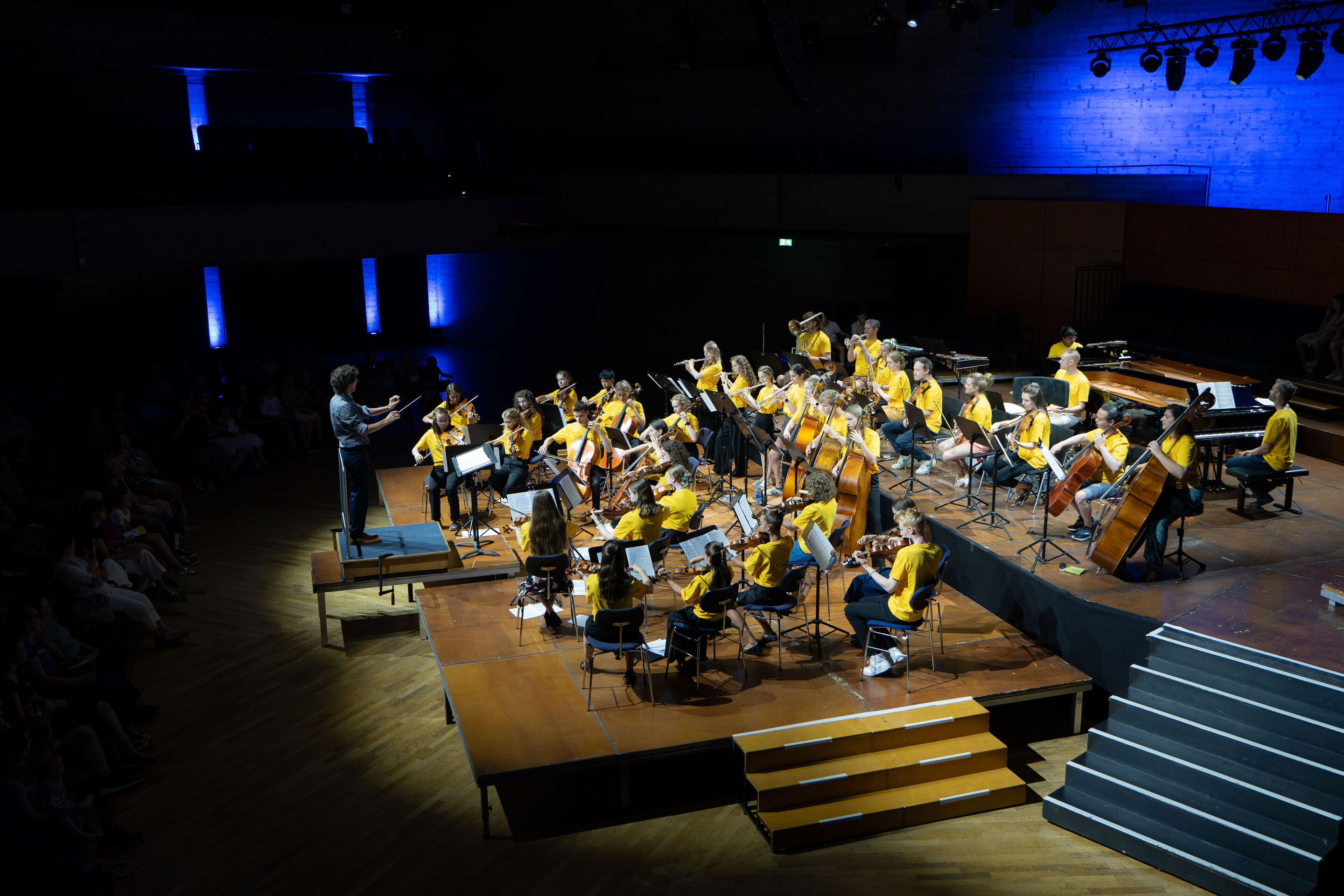 Öffentlicher Workshop mit Schülerinnen und Schülern der Region und dem Aurora Orchestra - Auf der Bühne des Festsaals Ingolstadt sind im hinteren Teil die Musiker des Aurora Orchestra zu sehen, davor musizieren Schülerinnen und Schüler, dirigiert von...