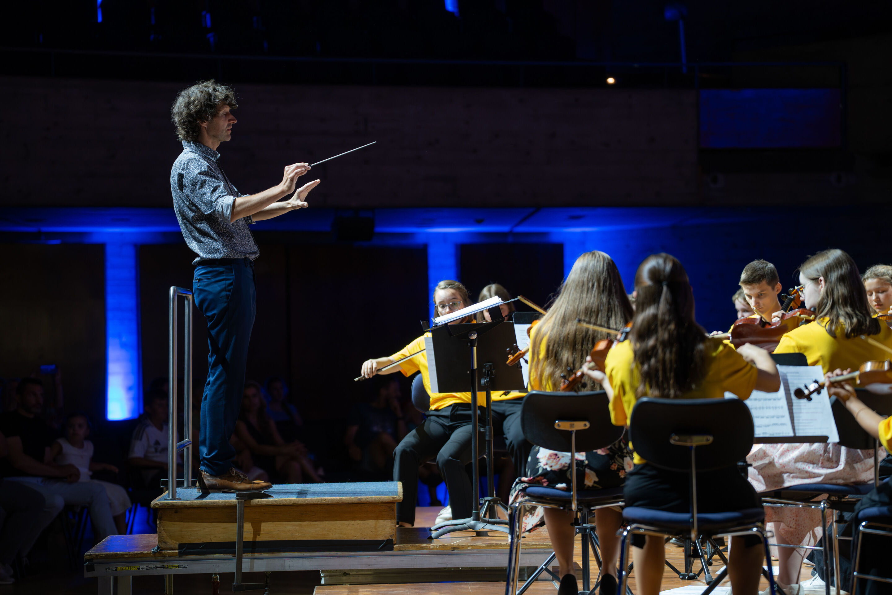Öffentlicher Workshop mit Schülerinnen und Schülern der Region und dem Aurora Orchestra - Klaus Hoffmann links im Bild dirigiert die Schülerinnen und Schüler aus der Region auf der Bühne des Festsaals in Ingolstadt.