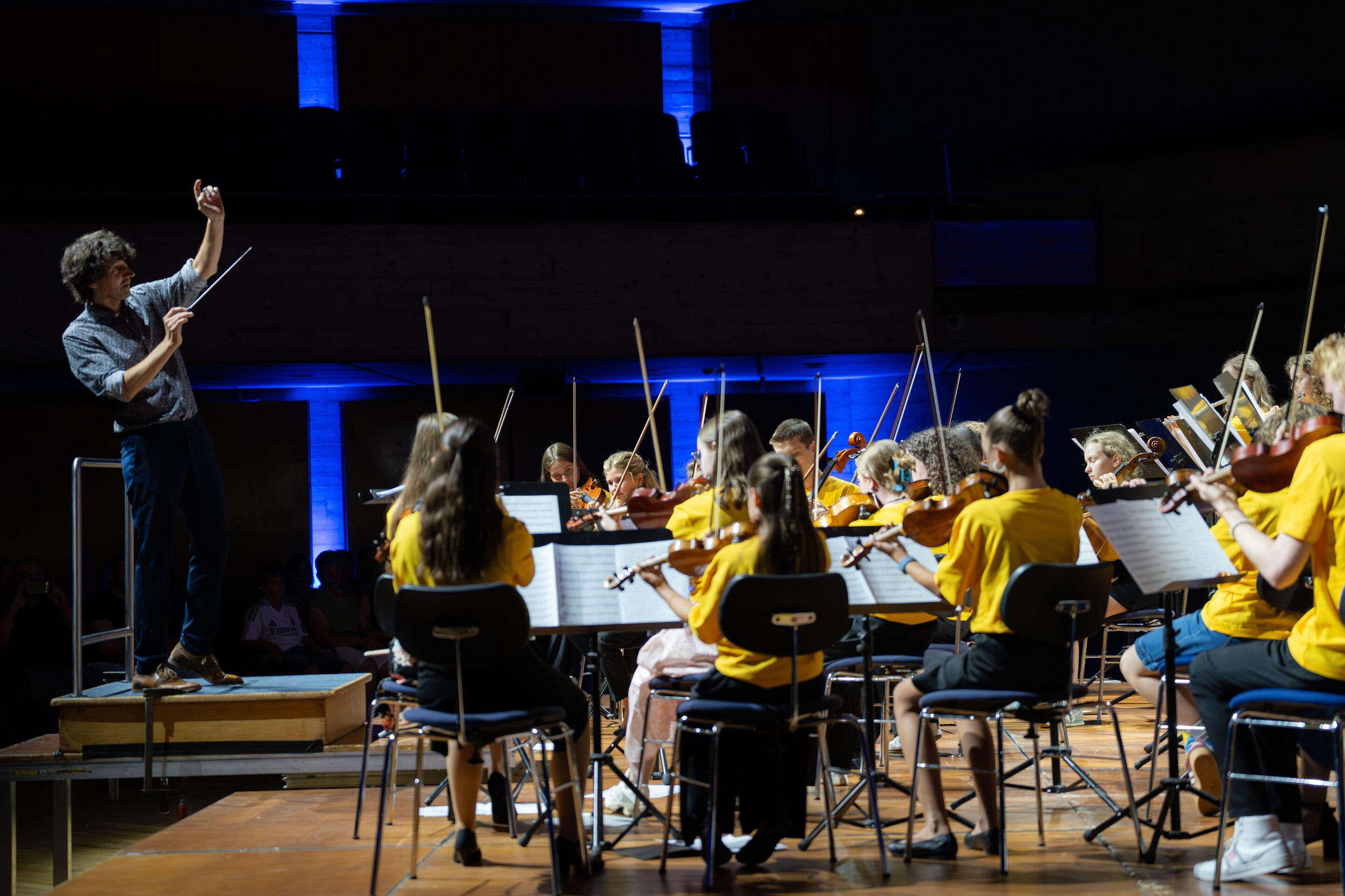 Öffentlicher Workshop mit Schülerinnen und Schülern der Region und dem Aurora Orchestra - Klaus Hoffmann dirigiert die musizierenden Schülerinnen und Schüler auf der Bühne des Festsaals Ingolstadt.
