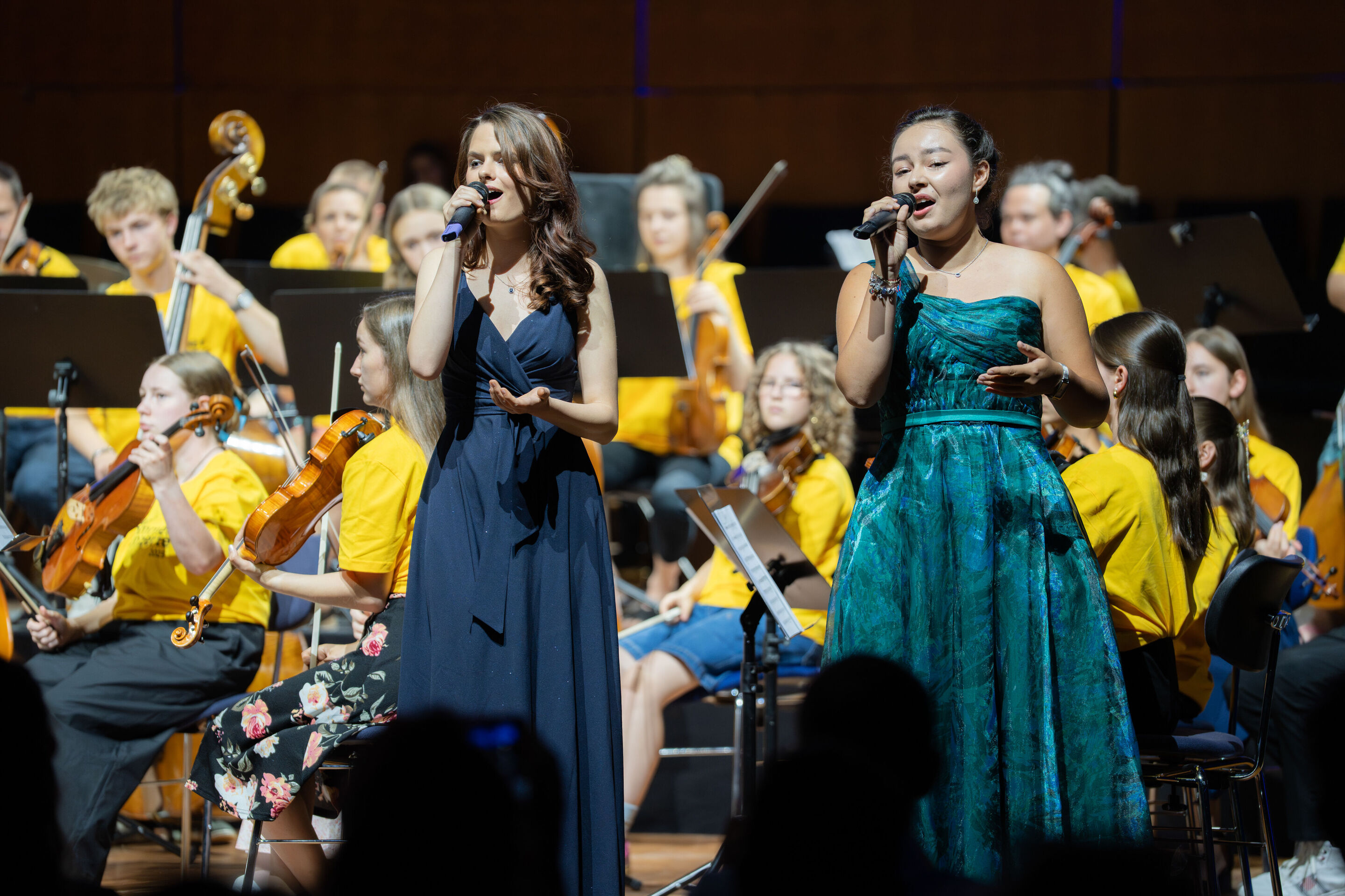 Öffentlicher Workshop mit Schülerinnen und Schülern der Region und dem Aurora Orchestra - Die Solistinnen Sarah Seyfert und Miriam Werner (Schülerinnen, 11. Klasse, Gnadenthal-Gymnasium) singen auf der Bühne des Festsaals Ingolstadt. Im Hintergrund sitzend...