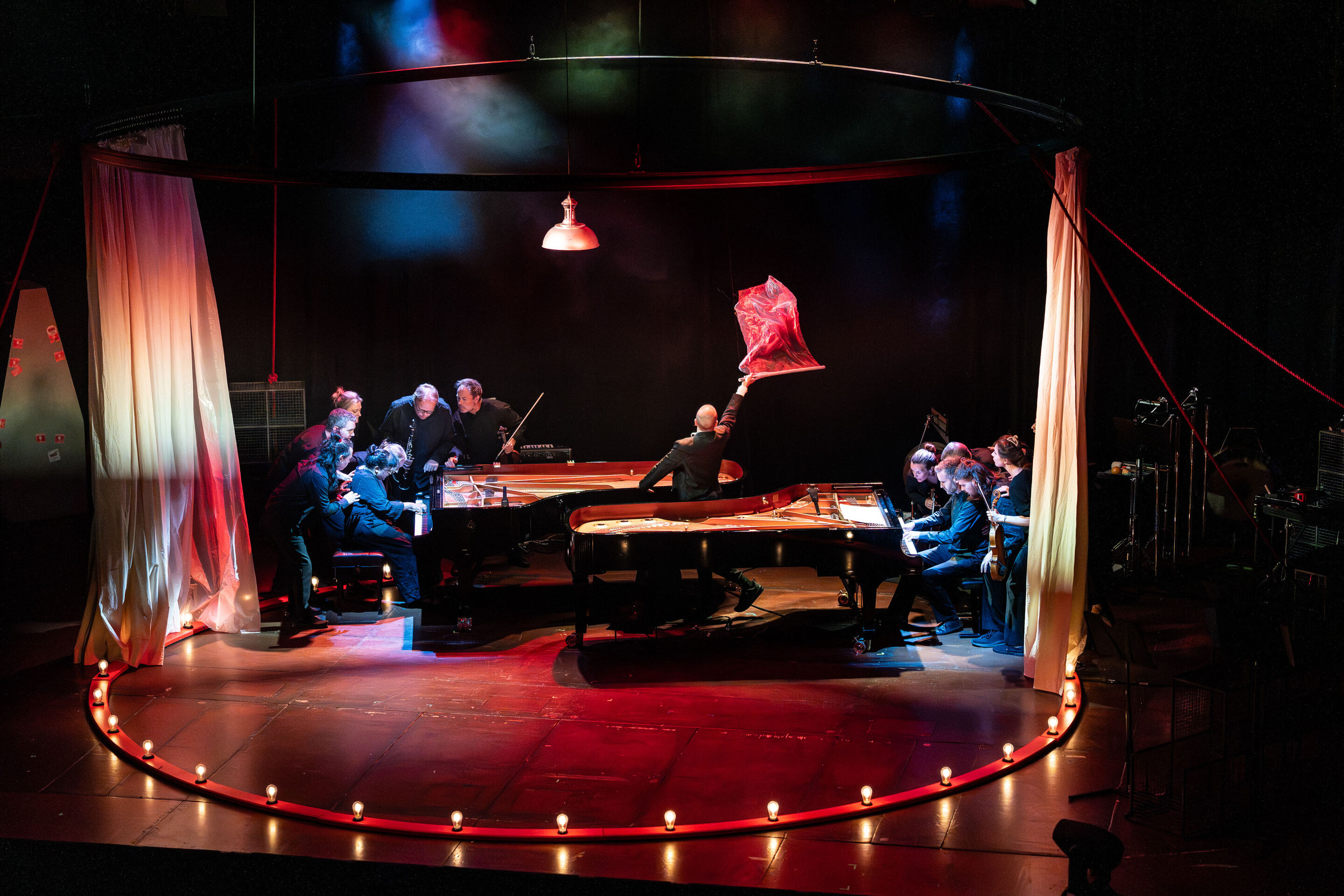 “Carnival”: Theatrical concert for families about the fabulous world of instruments - On the stage of the Festival Hall Ingolstadt, two pianos can be seen within a circle of light. Around the playing pianists stand the members of the Aurora Orchestra....