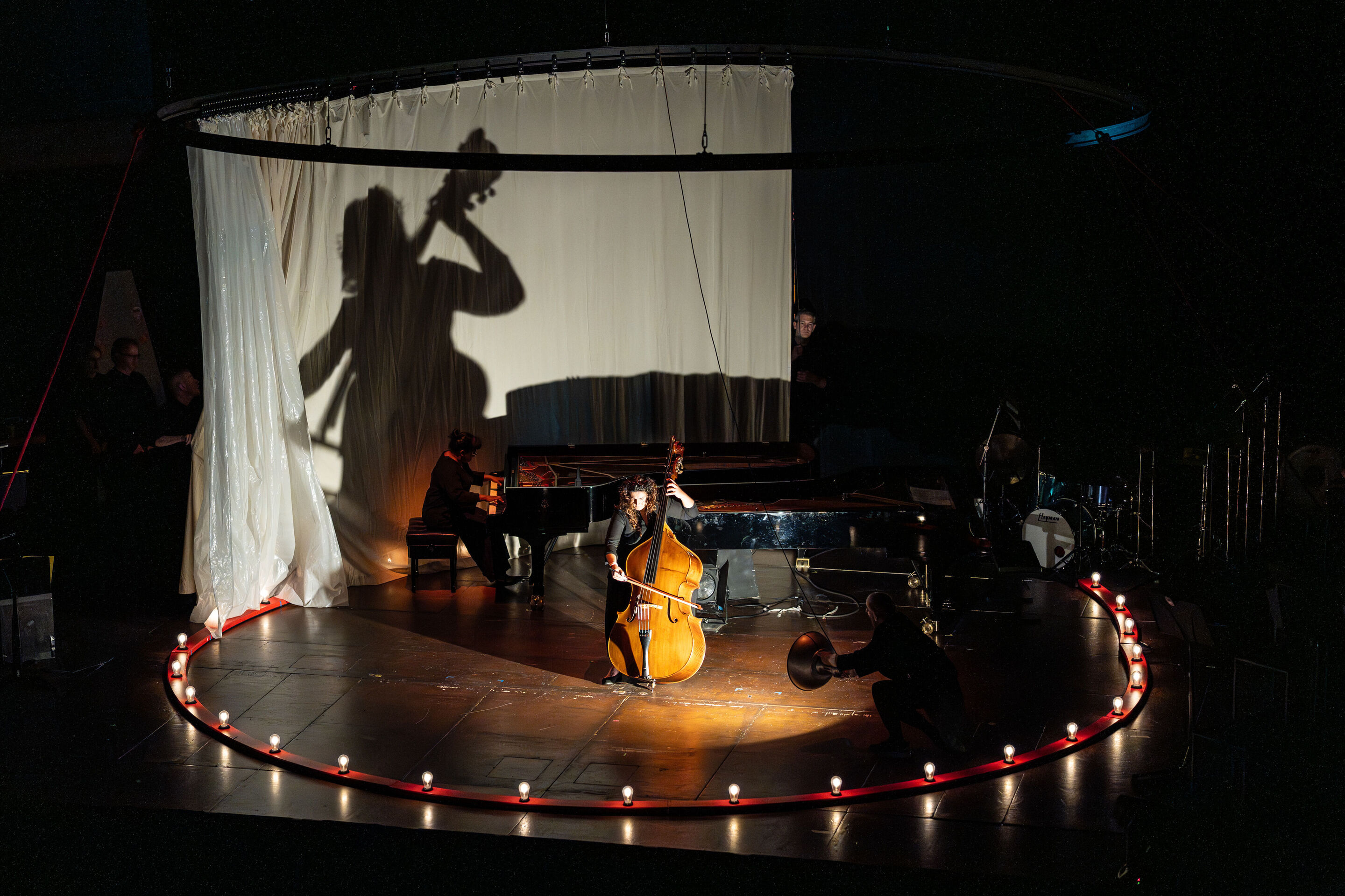 “Carnival”: Theatrical concert for families about the fabulous world of instruments - On the stage of the Festival Hall Ingolstadt, a member of the Aurora Orchestra plays the double bass in the center, while a pianist performs in the background. Dancer...