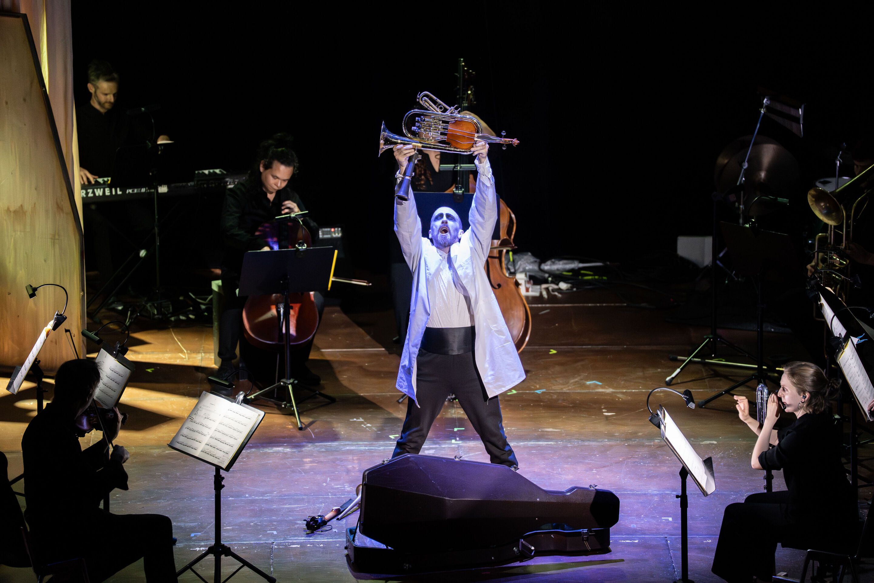 “Carnival”: Theatrical concert for families about the fabulous world of instruments - On the stage of the Festival Hall Ingolstadt, dancer Christopher Akrill can be seen in the center, holding a fantasy instrument up high.