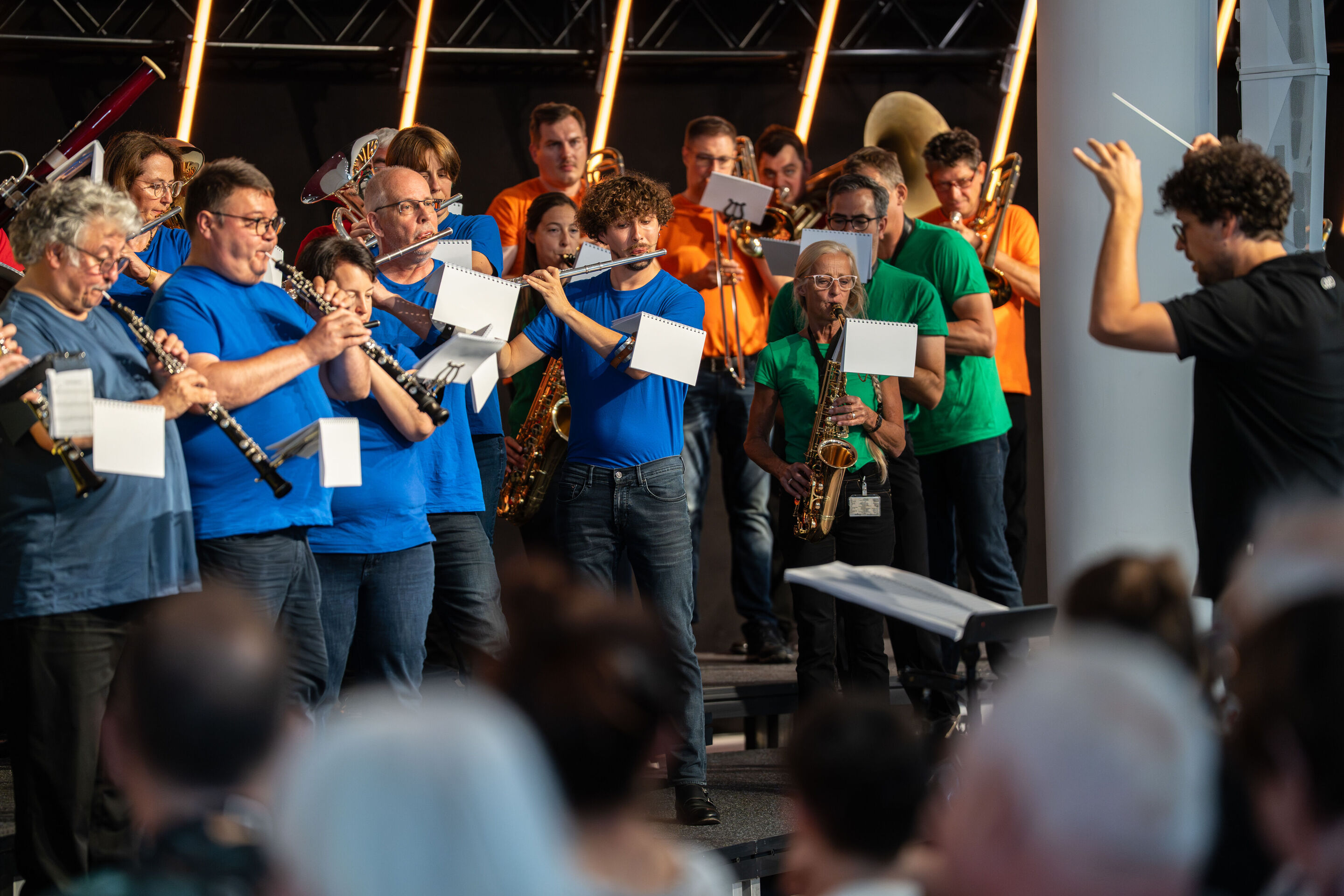 “ADUI und die Kraft der magischen Ringe”: children’s concert with the Audi Philharmonic Wind Orchestra - The Audi Philharmonic Wind Orchestra is performing on stage. Conductor Pietro Sarno can be seen on the right side of the image. The musicians are...