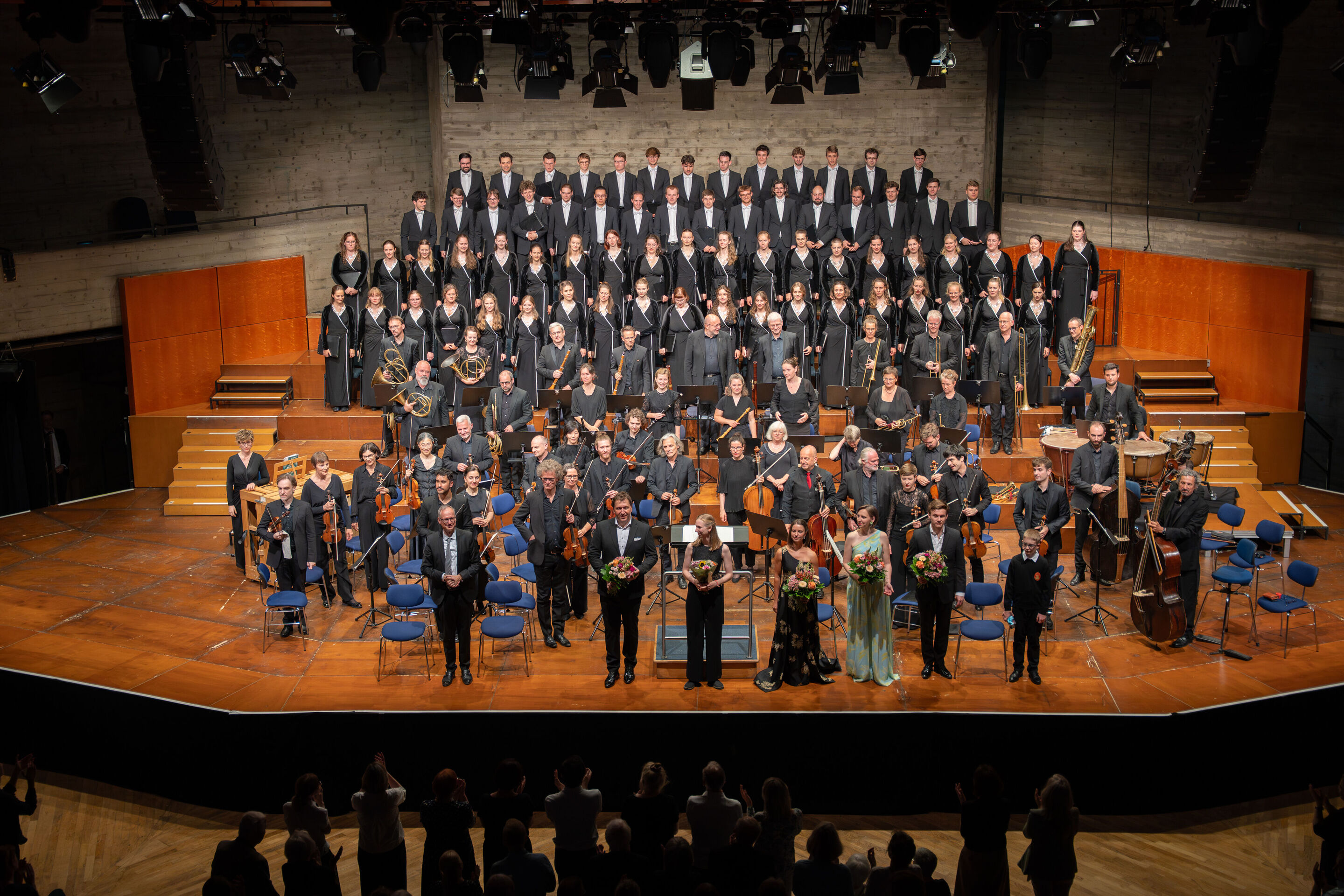 Mendelssohns „Elias“ mit der Audi Jugendchorakademie - Auf der Bühne im Festsaal Ingolstadt stehen aus Sicht des Publikums vorne die Solistinnen und Solisten mit Dirigent Martin Steidler. Dahinter die Musizierende der Akademie für Alte Musik Berlin und...