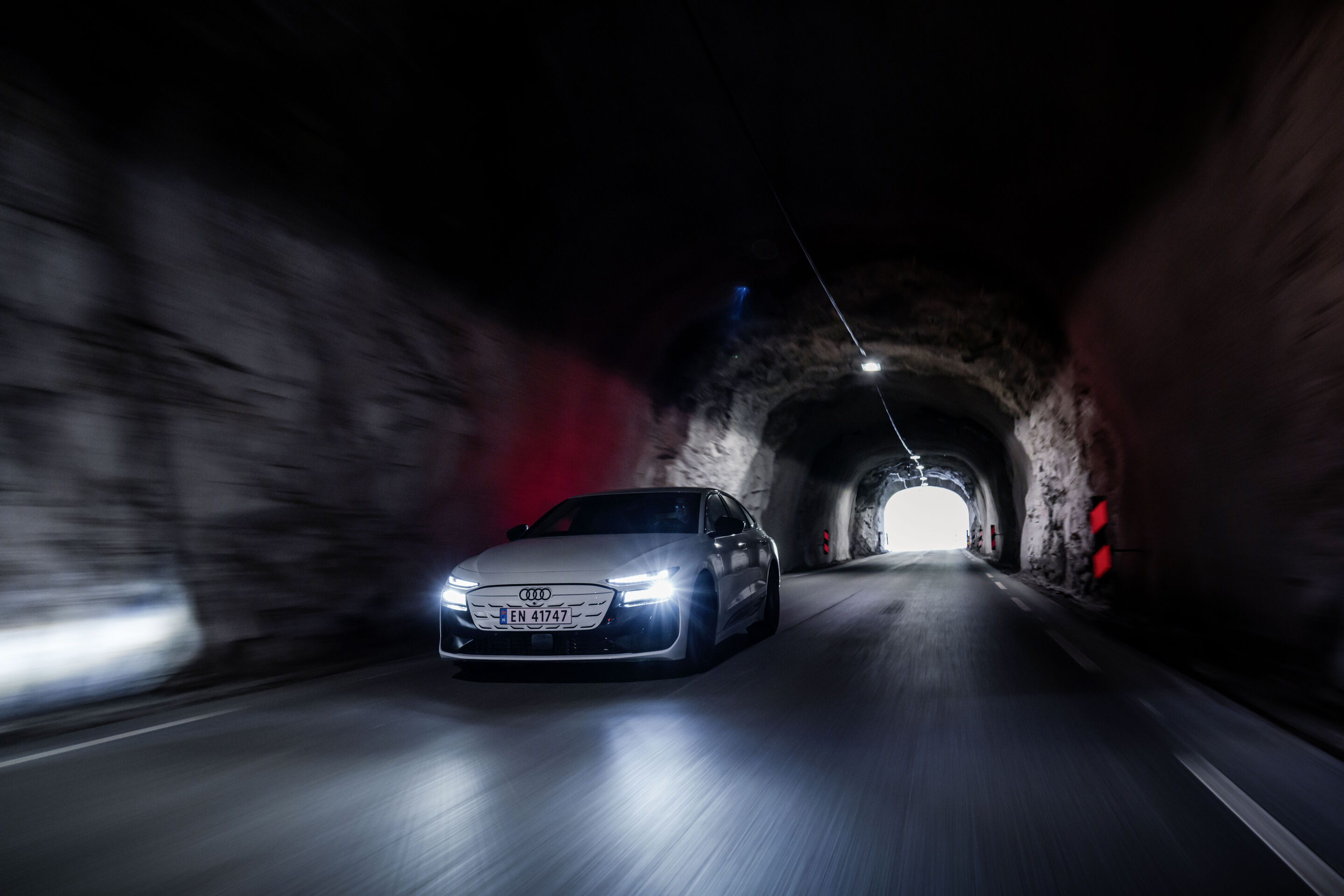 Strom aufwärts: Im Audi A6 e-tron von Kopenhagen nach Bergen - Ein Audi A6 Sportback e-tron in Gletscherweiß Metallic fährt mit eingeschaltetem Licht durch einen schwach beleuchteten Tunnel.