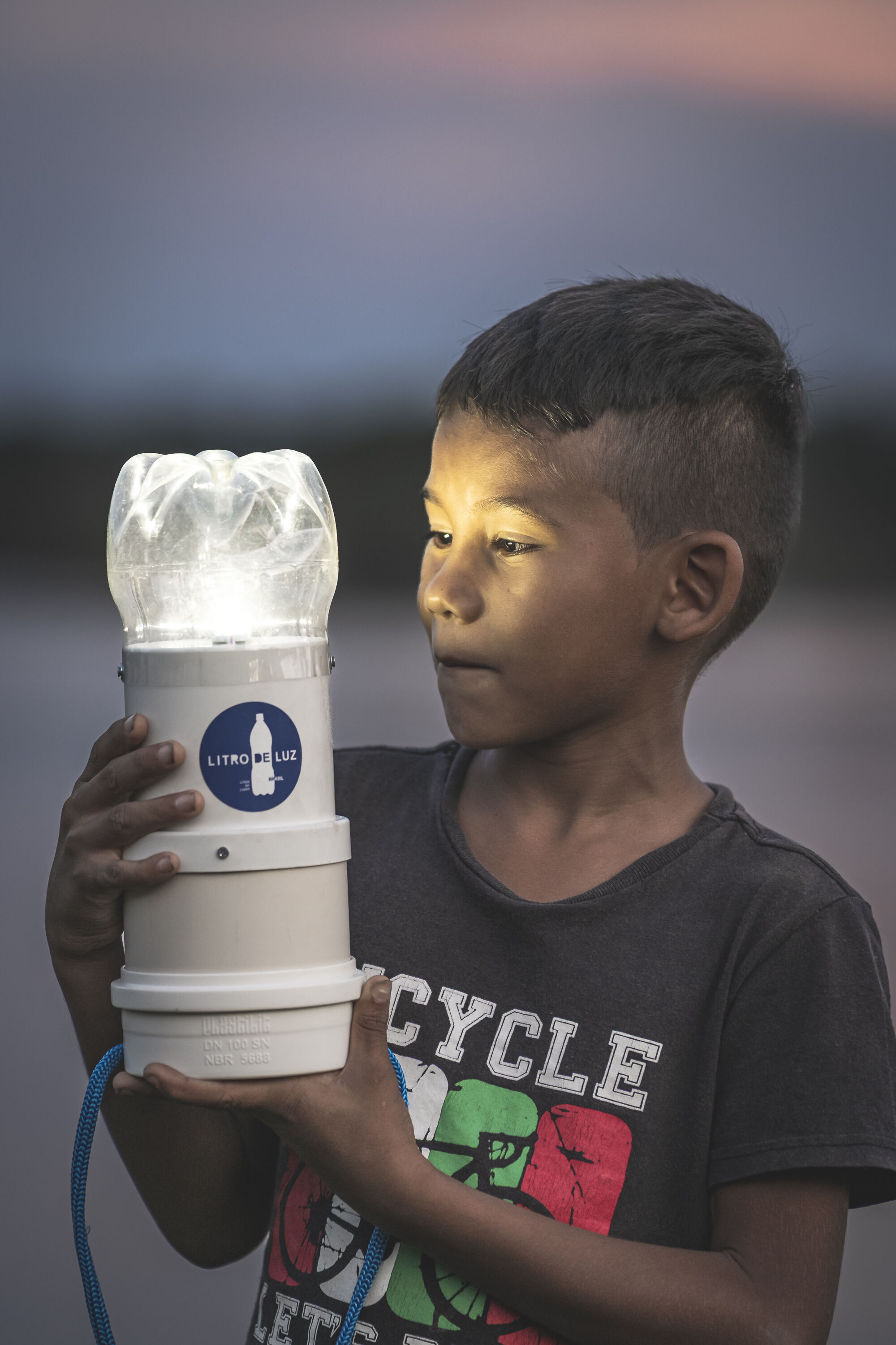 Solar lamps for Amazon communities without electricity: Audi and Litro de Luz continue partnership - A Brazilian boy holds a solar-powered street lamp in his hands, which is lit up in the darkness.