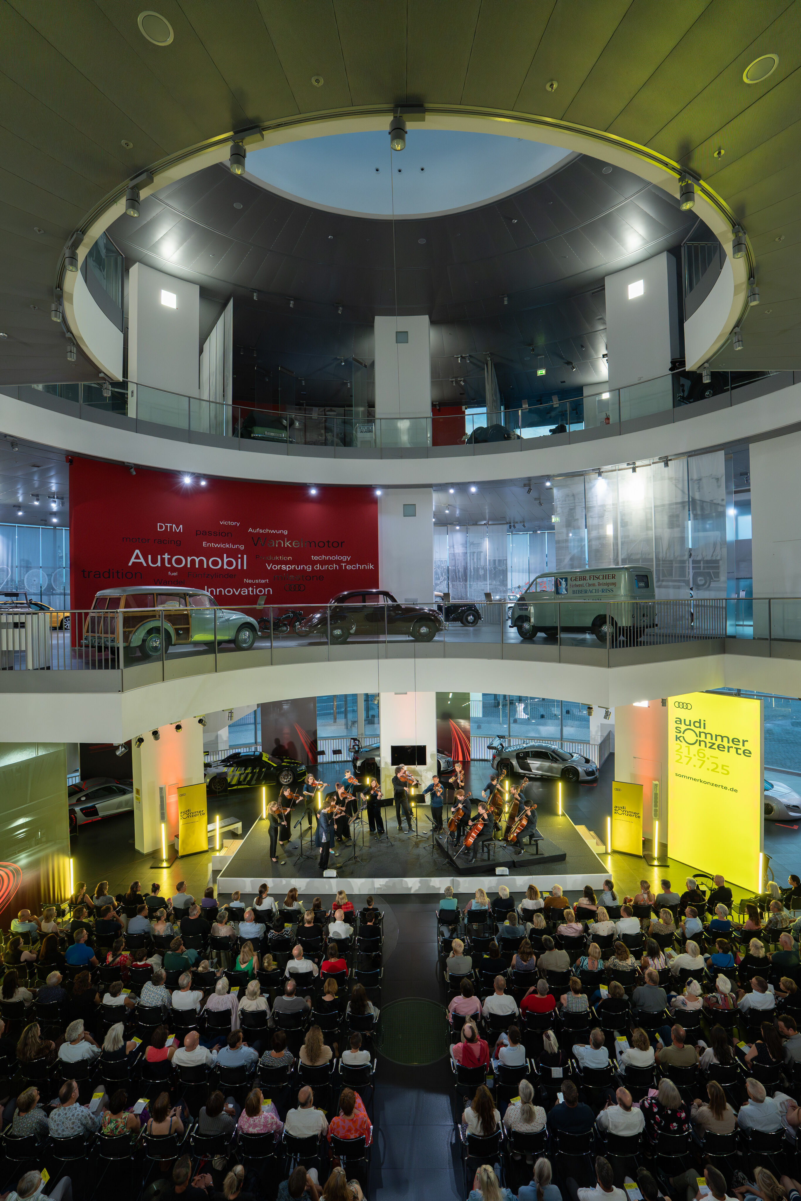 “Crossing over the Atlantic”: from Britten to Nirvana with the O/Modernt chamber orchestra - On the first level of the Audi museum mobile, the O/Modernt Chamber Orchestra, conducted by Hugo Ticciati, faces the audience. Above,  two levels of the permanent...