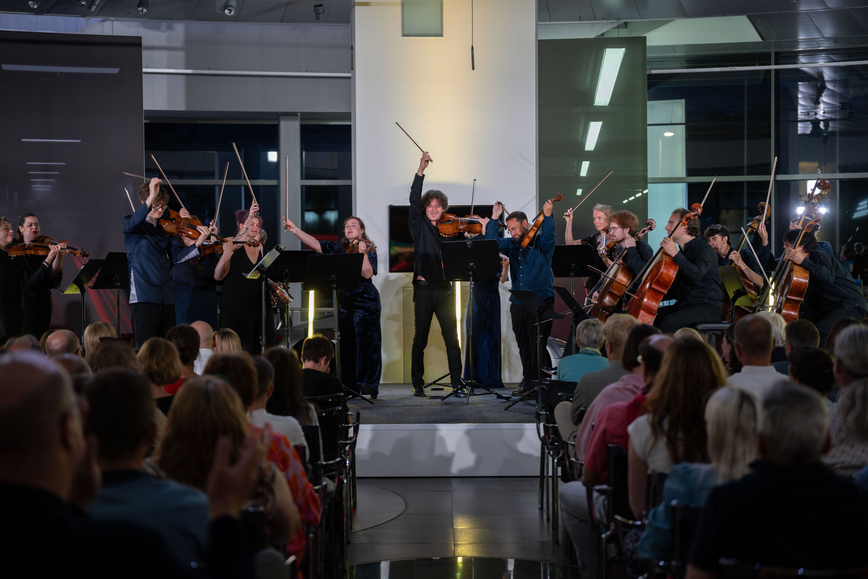 “Crossing over the Atlantic”: from Britten to Nirvana with the O/Modernt chamber orchestra - From the audience’s perspective, the O/Modernt Chamber Orchestra, conducted by Hugo Ticciati, is seen on the stage of the Audi museum mobile.