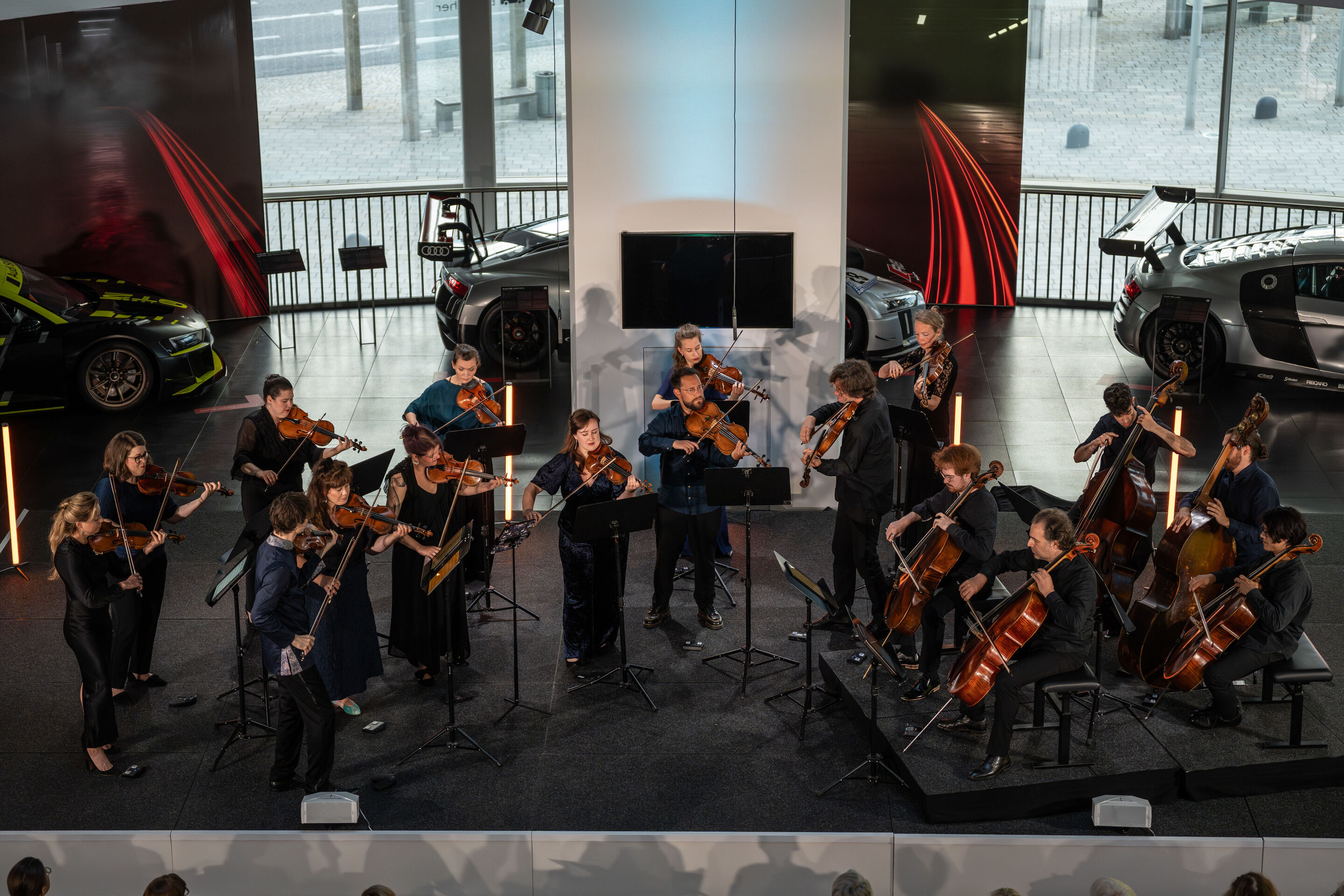 “Crossing over the Atlantic”: from Britten to Nirvana with the O/Modernt chamber orchestra - Orchestra, under the direction of Hugo Ticciati, on the stage of the Audi museum mobile . Behind exhibits from the “Audi R8 – Generations of Performance” exhibition.