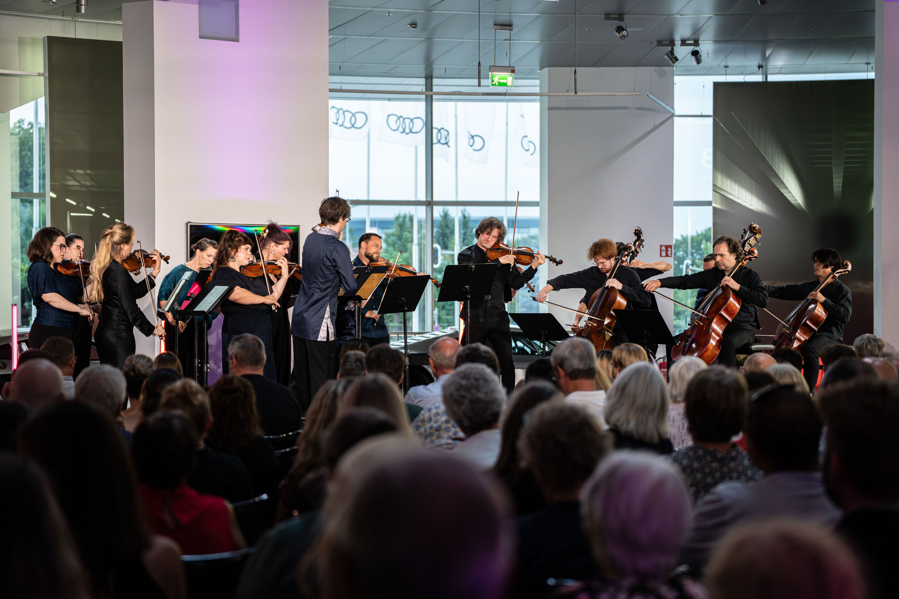 “Crossing over the Atlantic”: from Britten to Nirvana with the O/Modernt chamber orchestra - From the audience’s perspective, the O/Modernt Chamber Orchestra, conducted by Hugo Ticciati, on the stage of the Audi museum mobile.