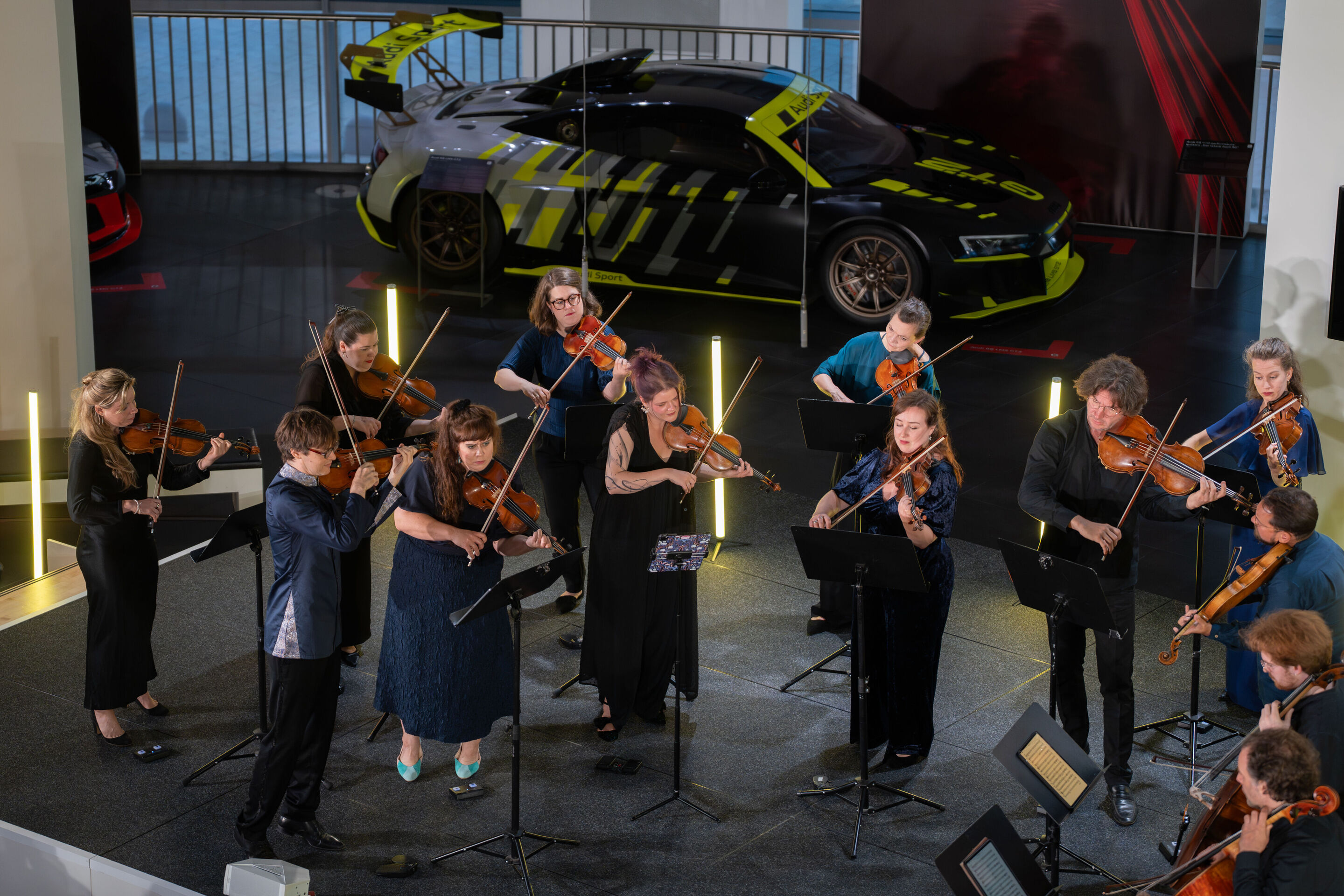 “Crossing over the Atlantic”: from Britten to Nirvana with the O/Modernt chamber orchestra - From a bird’s-eye view, part of the O/Modernt Chamber Orchestra, conducted by Hugo Ticciati, is seen on the stage of the Audi museum mobile.