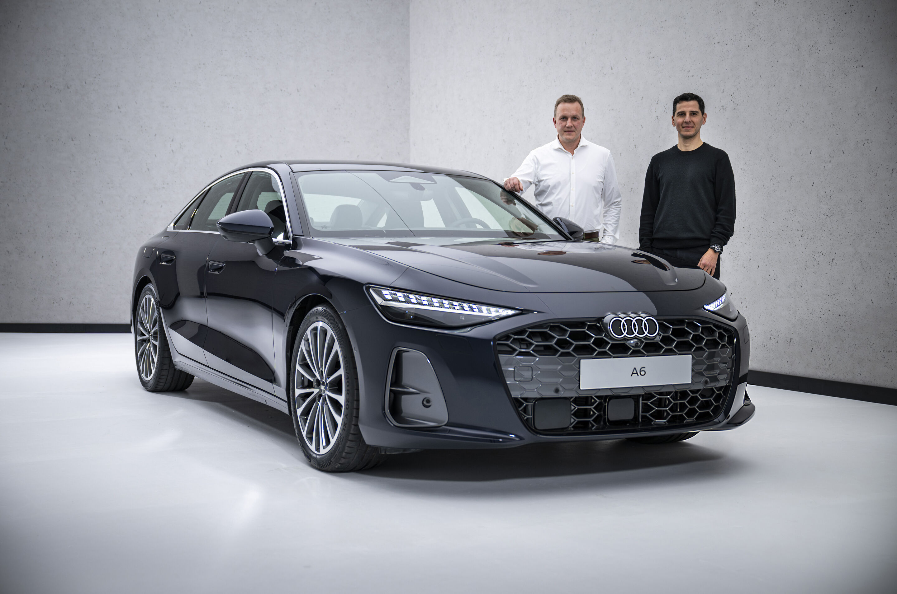 The new A6 Sedan launches across retail locations - Aerodynamics developer Sebastian Weiper (left) and exterior designer Francesco d’Amore (right) stand next to the Audi A6 Sedan.