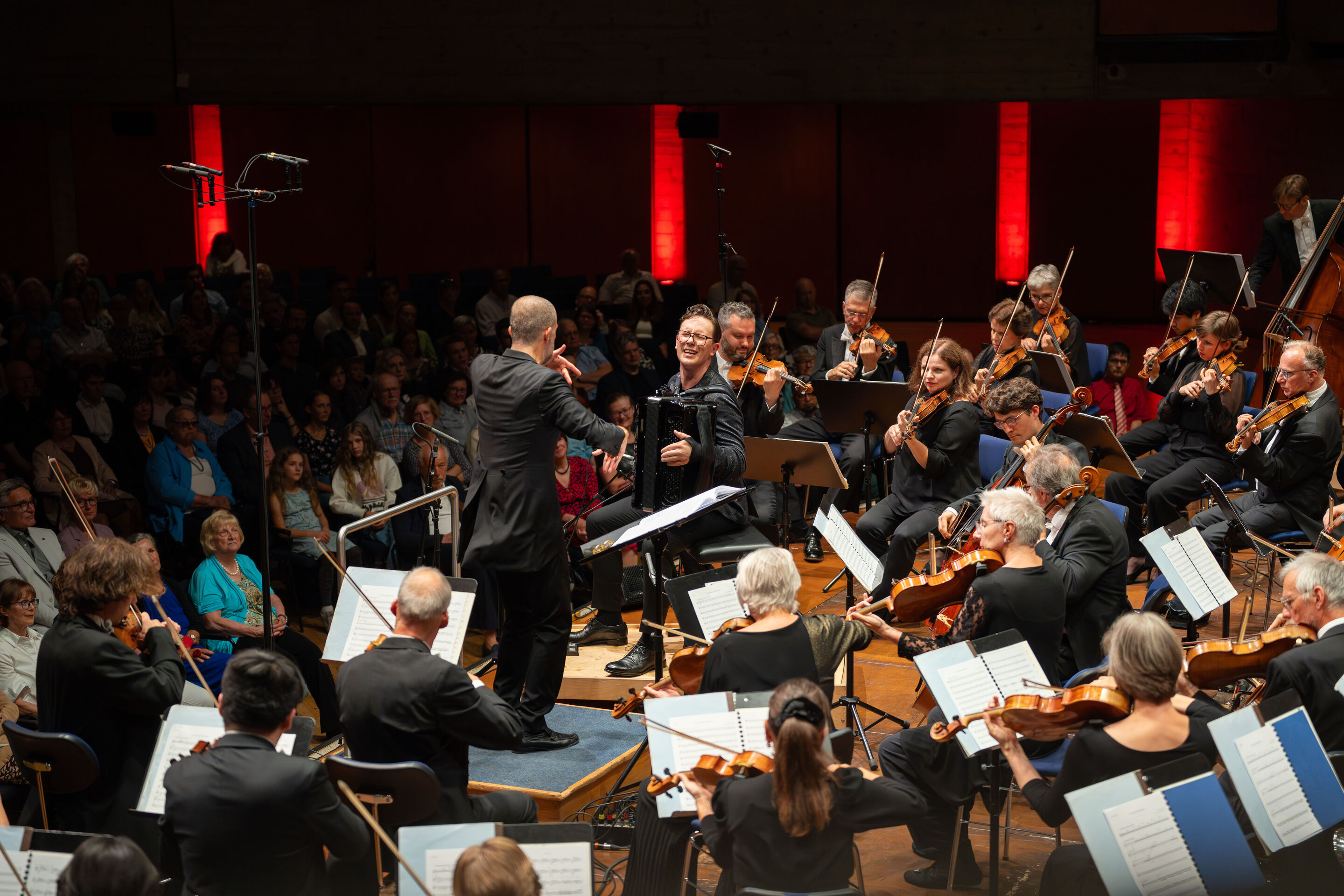 Closing concert with accordion star Martynas Levickis and the Deutsche Kammerphilharmonie Bremen - On the stage of the Festival Hall Ingolstadt, Martynas Levickis plays his accordion, conducted by Omer Meir Wellber on the left side of the image. Around...