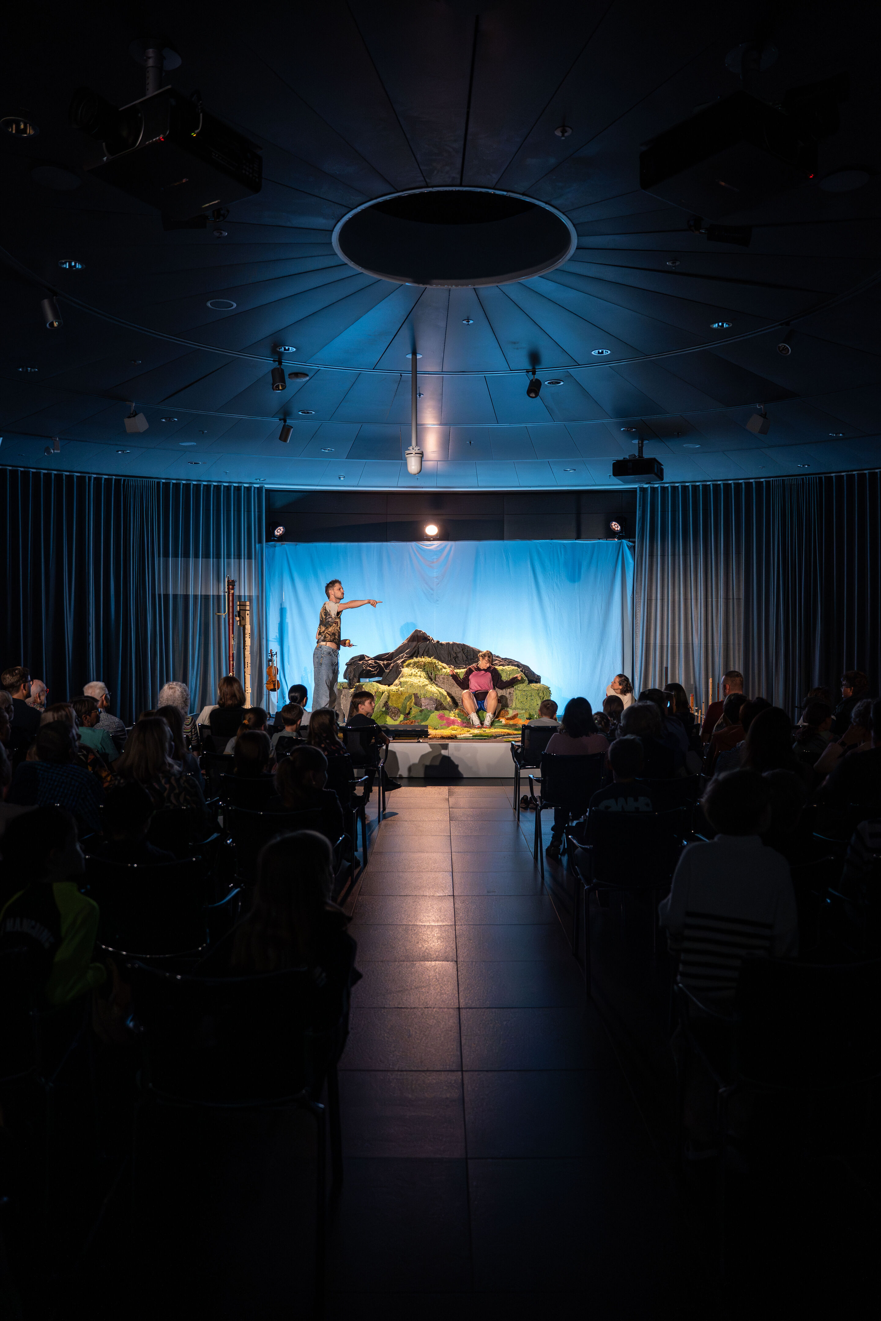 The Salzburg Festival presents: “Berge flüstern laut” – musical theater for children - From the view of the center aisle between the spectators: Franca Luisa Burandt and Matteo Haitzmann from the Salzburg Festival on the stage of the stage of the cinema...