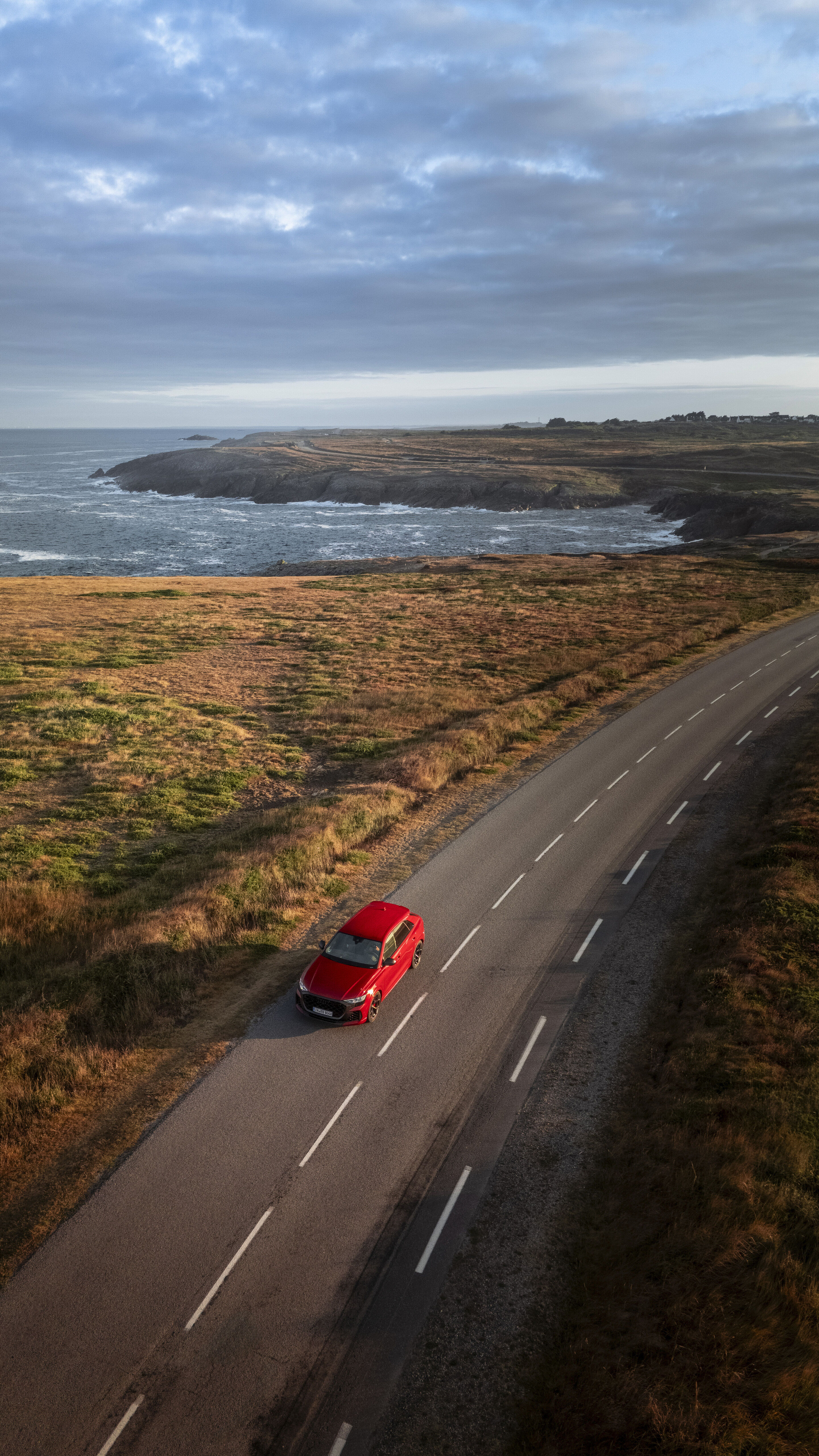 Audi RS Q8 SUV performance - Audi RS Q8 SUV performance in Chili Red Metallic on a coastal road with a view of the sea.