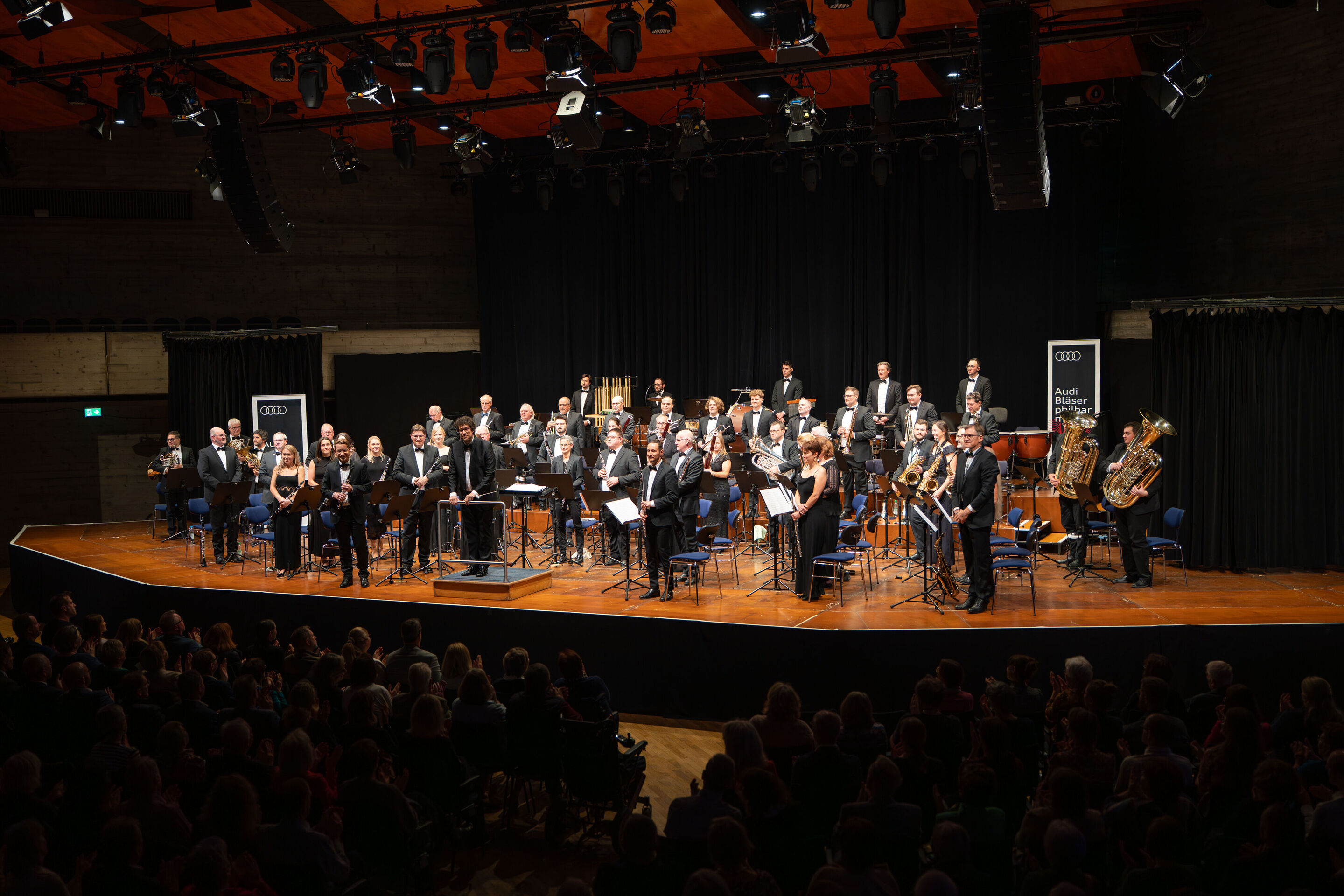 Benefizkonzert der Audi Bläserphilharmonie mit der Vienna Clarinet Connection - Das Ensemble der Audi Bläserphilharmonie steht beim traditionellen Benefizkonzert 2025 auf der Bühne im Festsaal Ingolstadt und erhält Applaus vom Publikum.