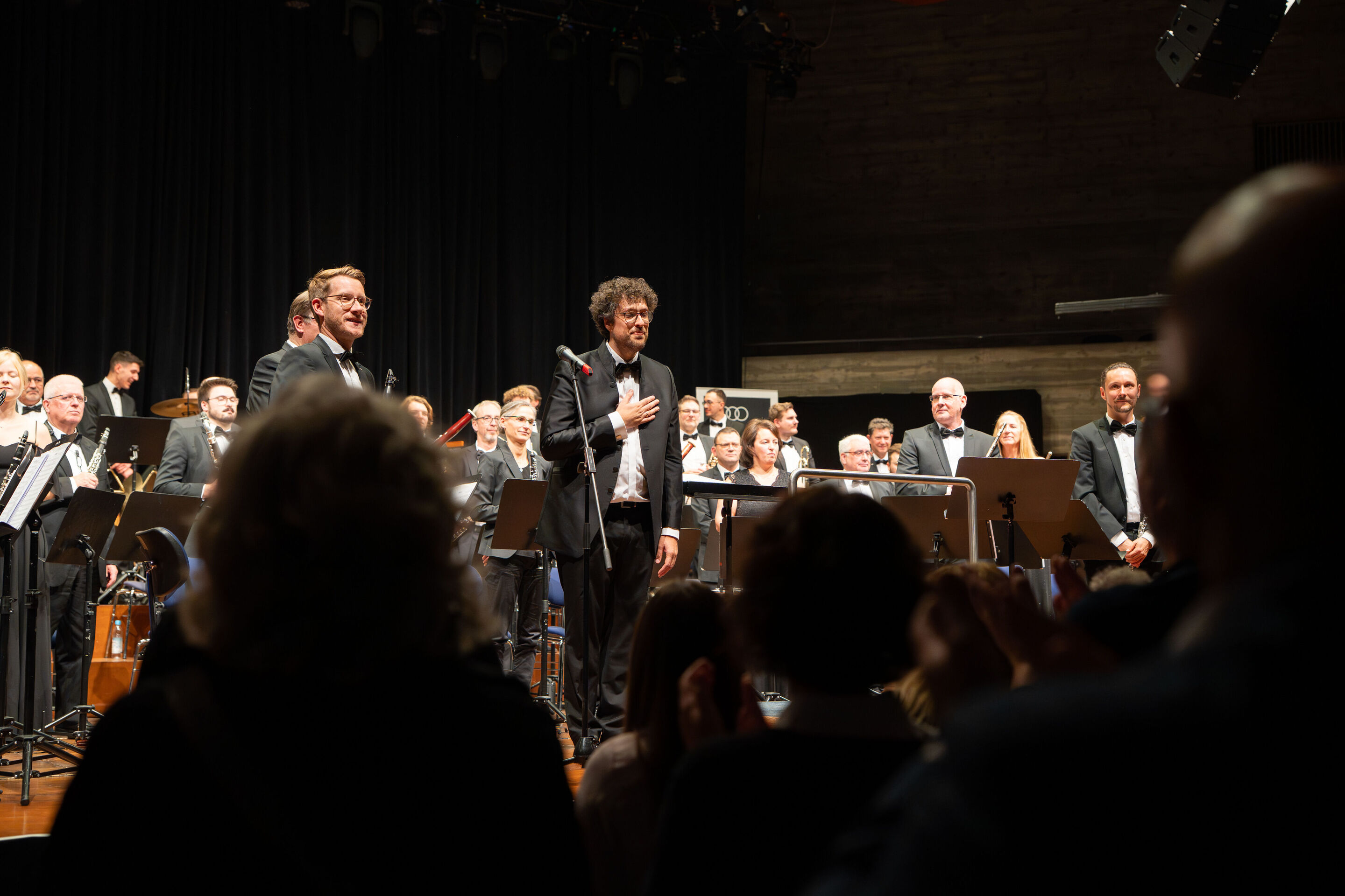 Benefizkonzert der Audi Bläserphilharmonie mit der Vienna Clarinet Connection - Pietro Sarno, künstlerischer Leiter der Audi Bläserphilharmonie, erhält beim Benefizkonzert 2025 Applaus vom Publikum und ist sichtlich ergriffen; hinter ihm steht das Ensemble...