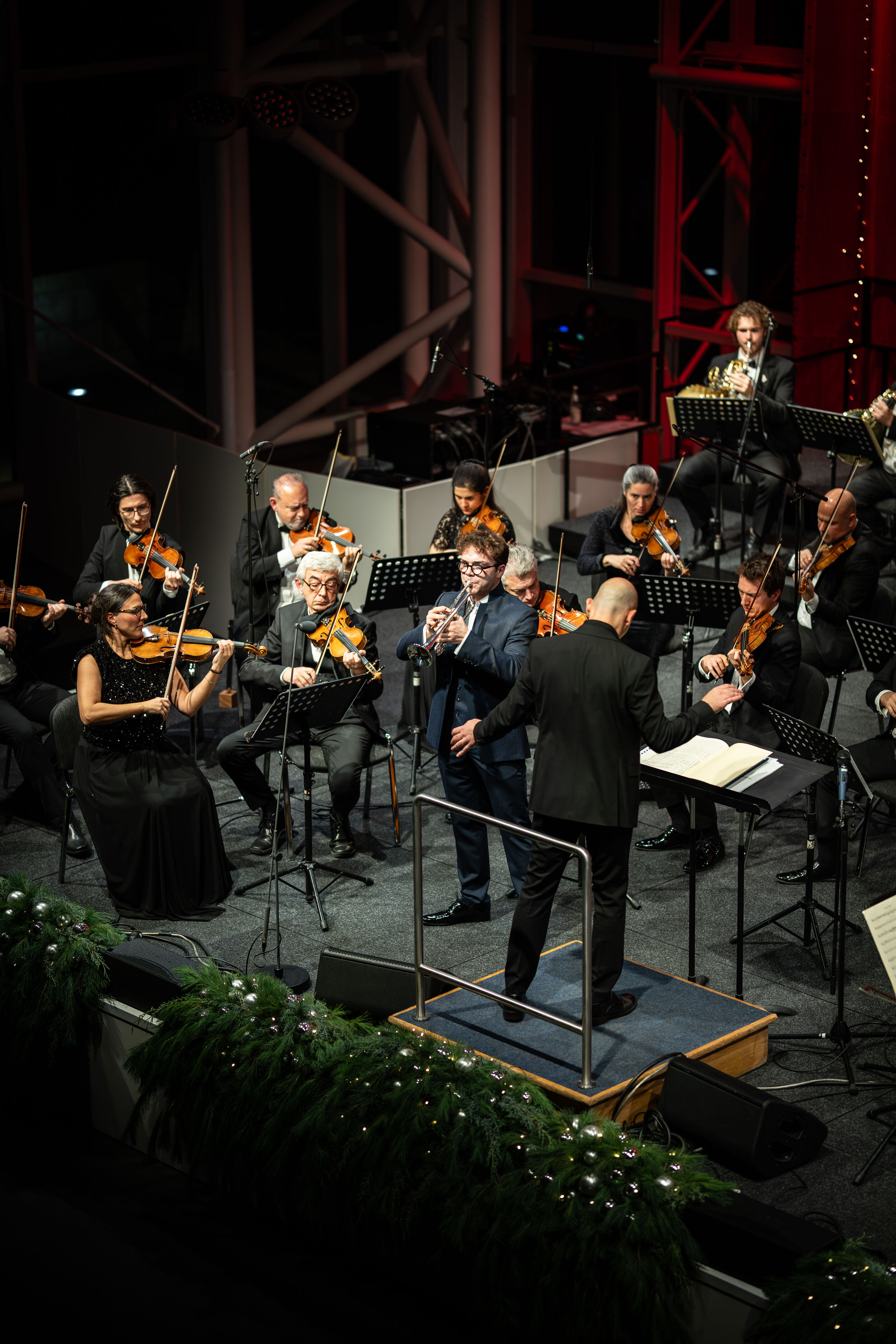 Audi Weihnachtskonzert 2025 - Trompeter Robin Paillet und die Kammerphilharmonie Ingolstadt, unter der Leitung von Ariel Zuckermann, auf der Bühne beim Audi Weihnachtskonzerts 2025