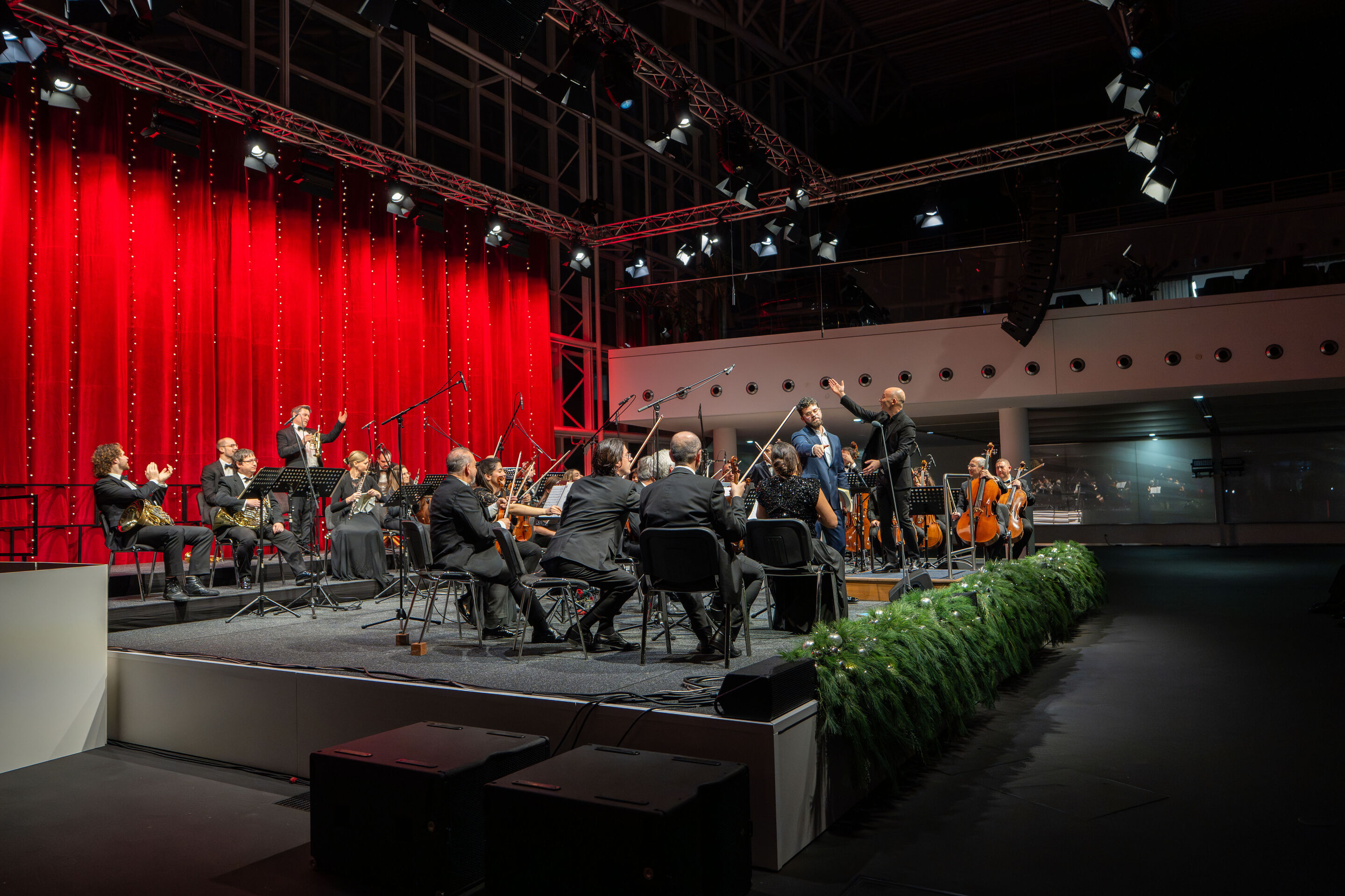 Audi Weihnachtskonzert 2025 - Vokalist Lukas Enoch Lemcke (Bass) und die Kammerphilharmonie Ingolstadt, unter Leitung von Dirigent Ariel Zuckermann, auf der Bühne beim Audi Weihnachtskonzert 2025 im Audi Forum Ingolstadt