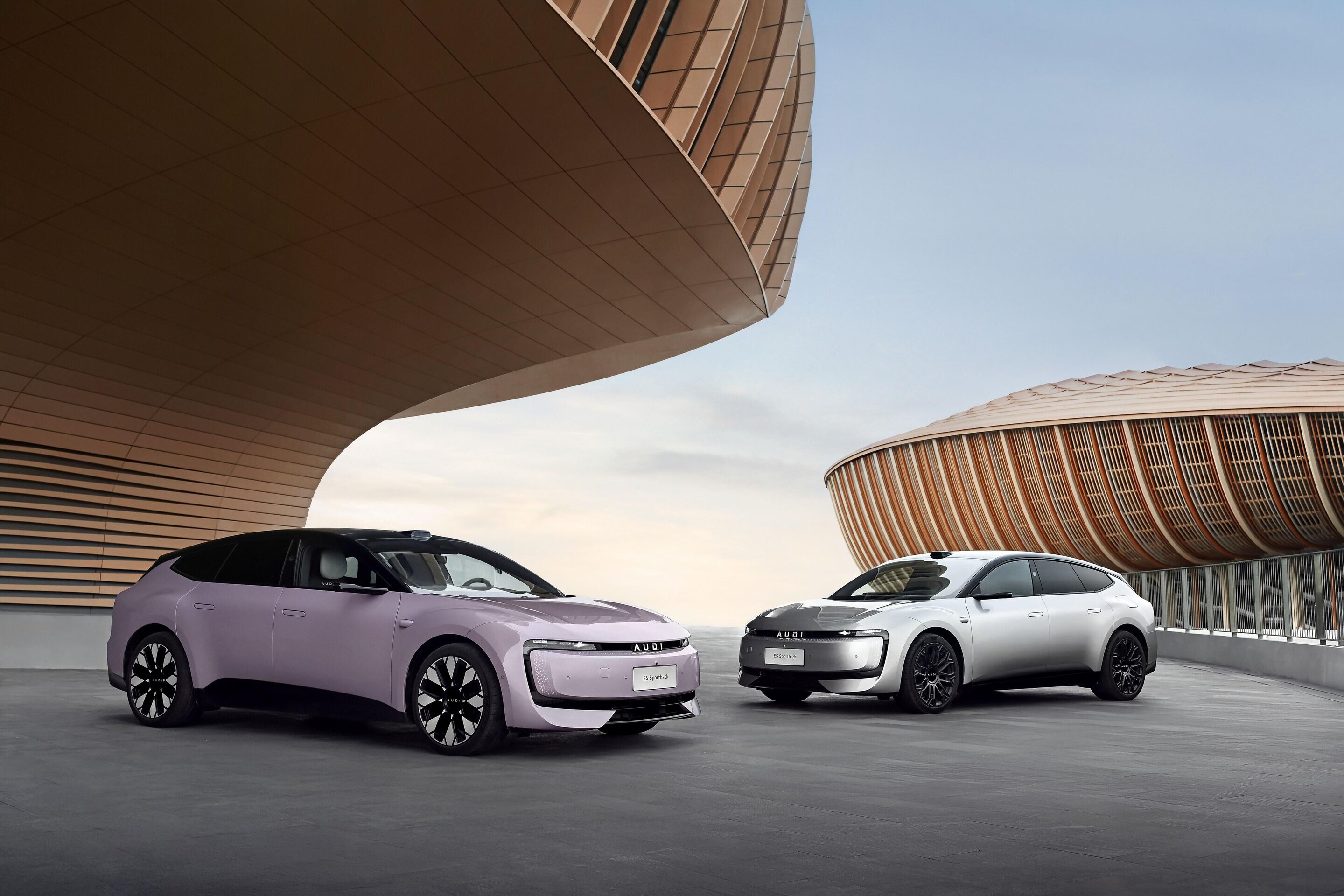 AUDI E5 Sportback named 2026 China Car of the Year - Two Audi E5 Sportback in pastel violet and white are positioned in front of modern architecture. The all-electric model, winner of the prestigious “China Car of the Year 2026” award, combines dynamic...