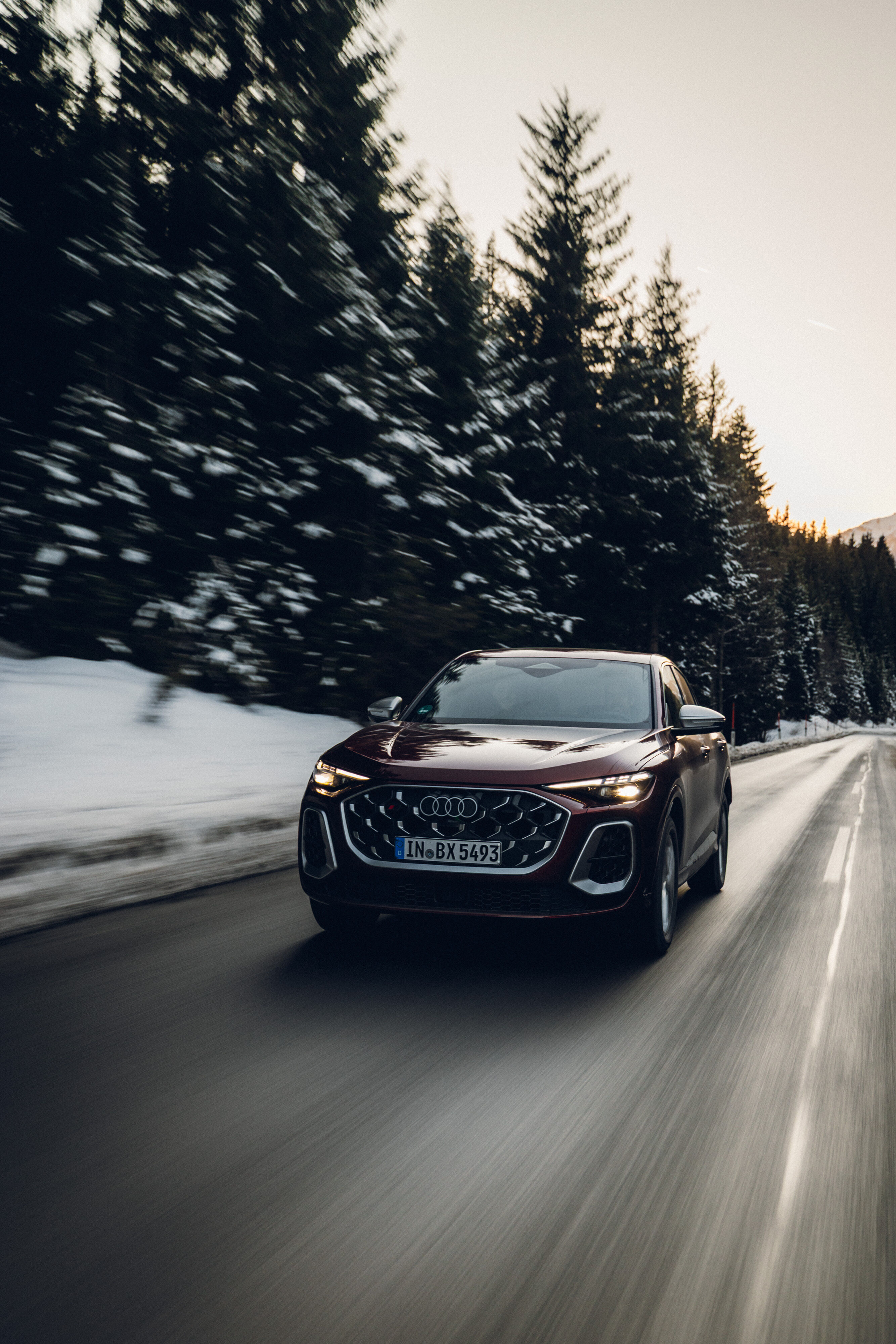 Audi SQ5 Sportback - An Audi SQ5 Sportback in Grenadine Red is driving along a winter mountain road. Snow lines the roadside.