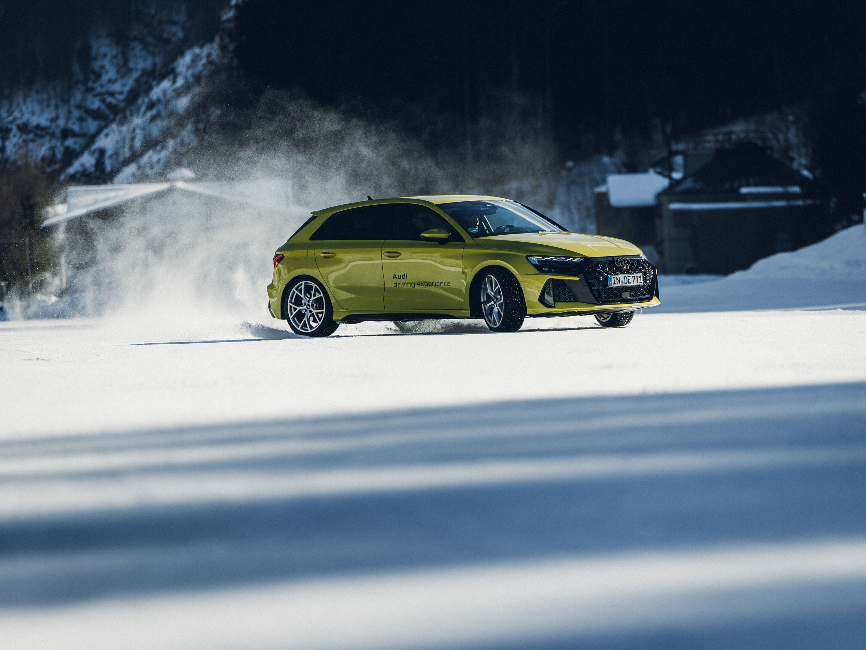 Audi RS 3 Sportback - An Audi RS 3 Sportback in Python Yellow is driving across a snowy surface, kicking up snow.