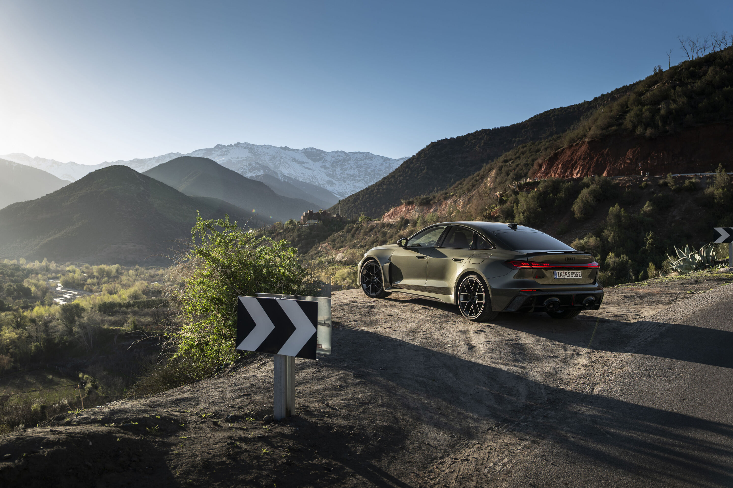 The Audi RS 5 Sedan - The Audi RS 5 Sedan in Bedford green at a winding mountain pass with views of snow‑covered peaks.