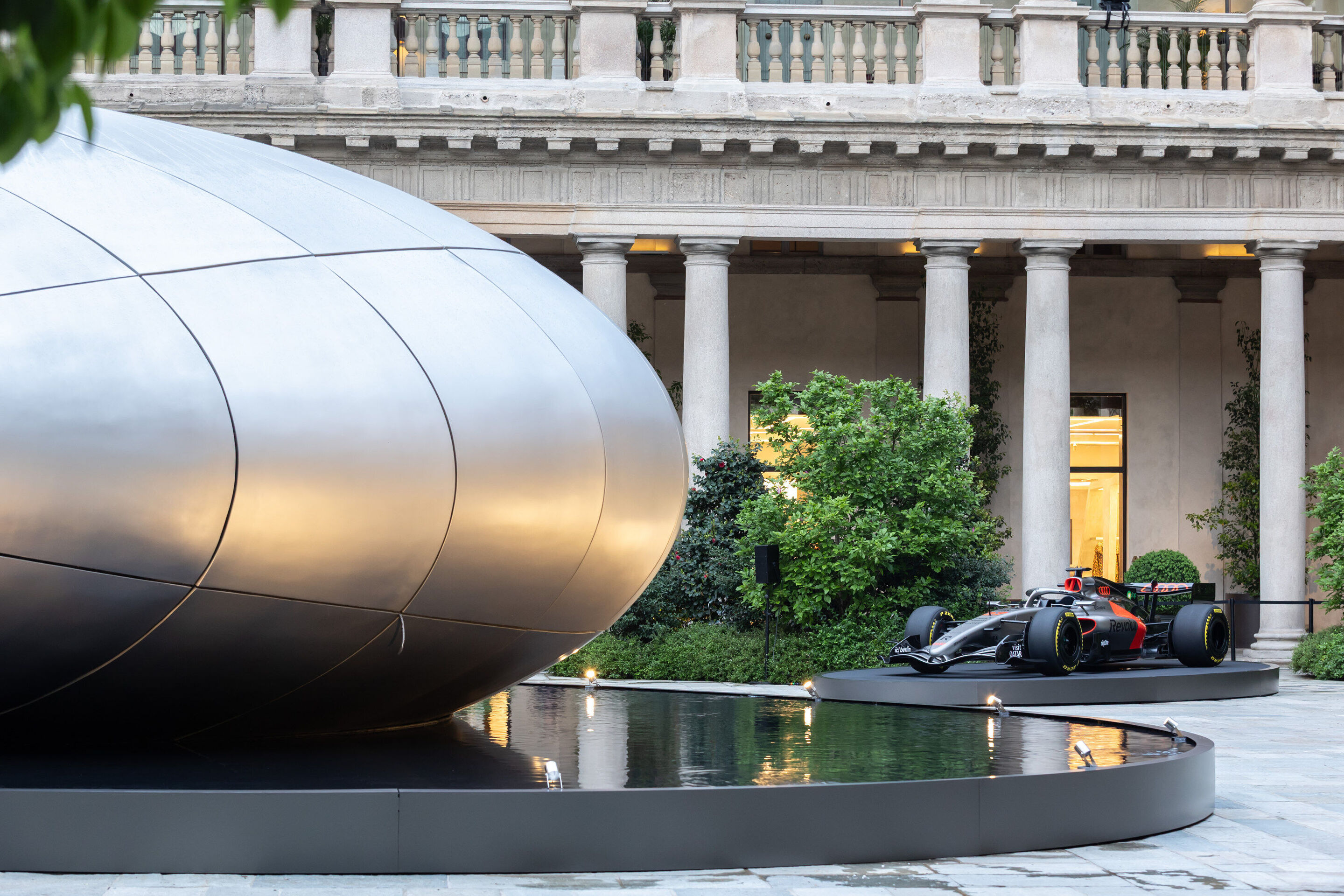 Audi at Milan Design Week 2026 - Side view of the installation “Origin”. In the background, the Audi Formula 1 show car Audi R26 is displayed.