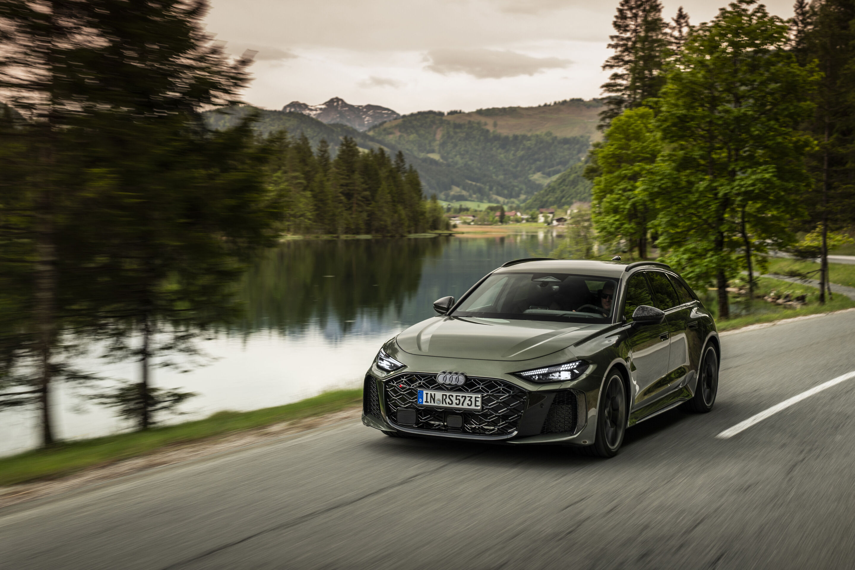 Audi RS 5 Avant - Audi RS 5 Avant in Bedford green, outdoor driving shot, exterior, front view on a road along a lake.