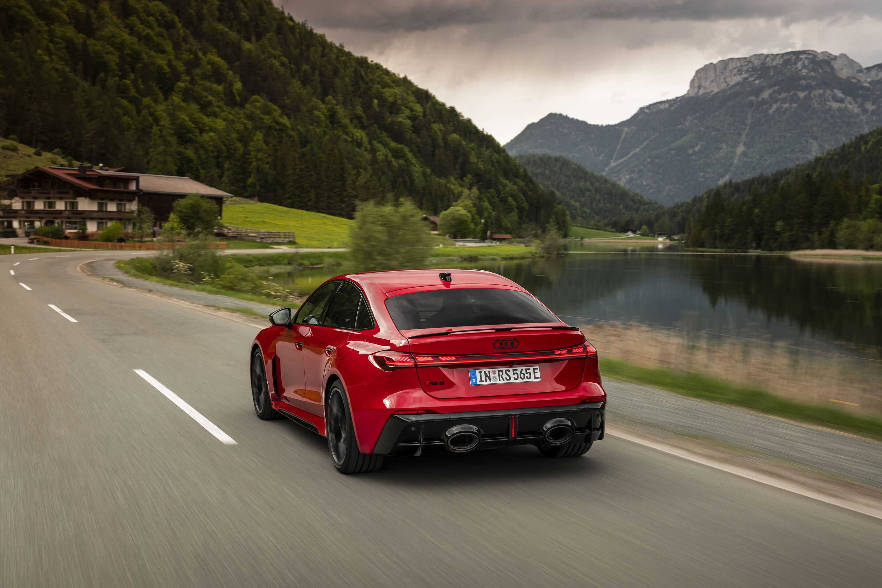 Audi RS 5 Sedan - Audi RS 5 Sedan in Progressive red, outdoor driving shot, exterior, rear view on a country road along a lake in an alpine setting.
