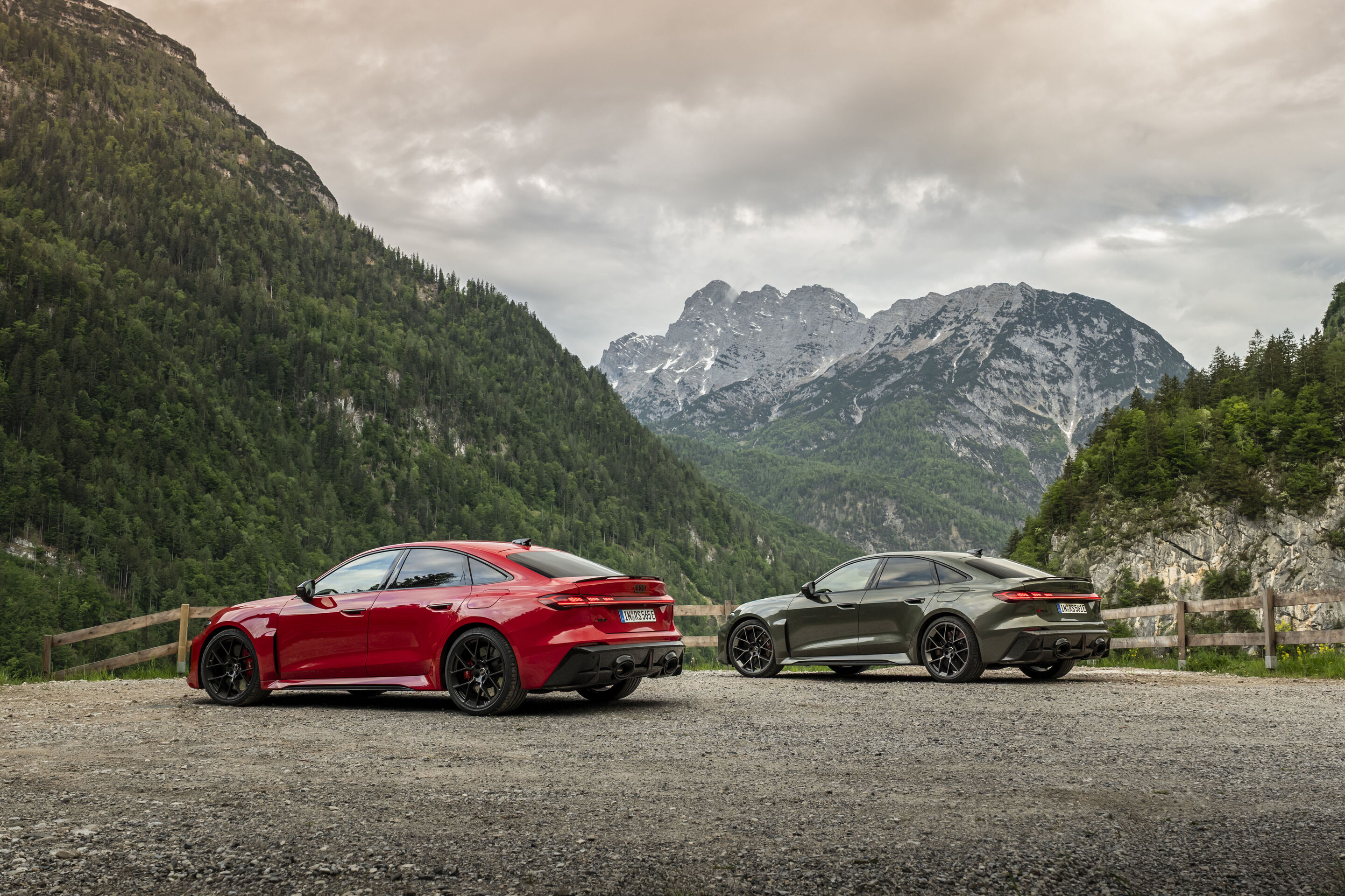 Audi RS 5 Sedan - From left in the image: Audi RS 5 Sedan in Progressive red and Audi RS 5 Sedan in Bedford green, outdoor static shot, exterior, in front of an alpine mountain backdrop.