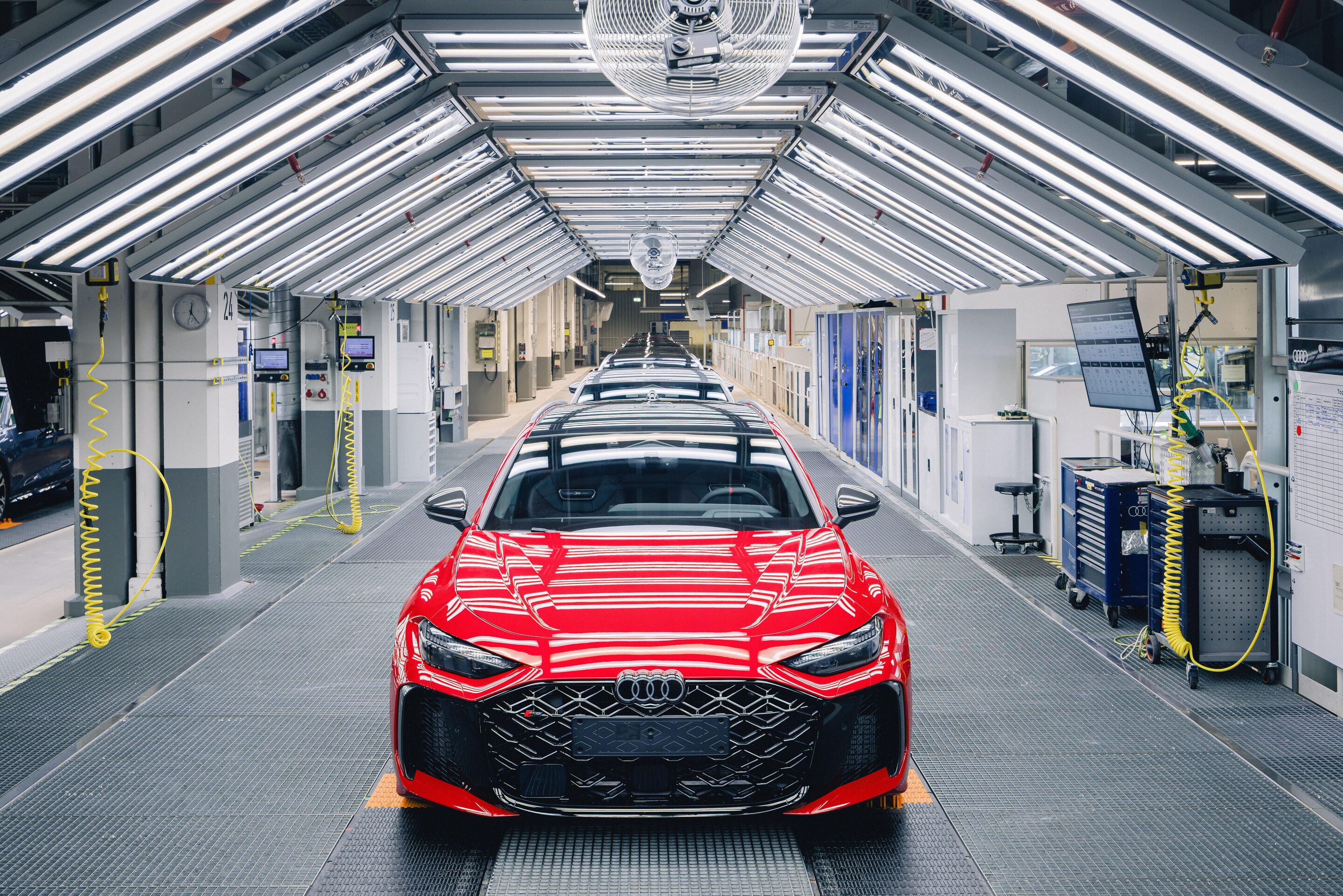 The new Audi RS 5: cross-site engine development - Audi RS 5 Avant in Progressive Red during a production step on the assembly line at the Audi plant in Neckarsulm.