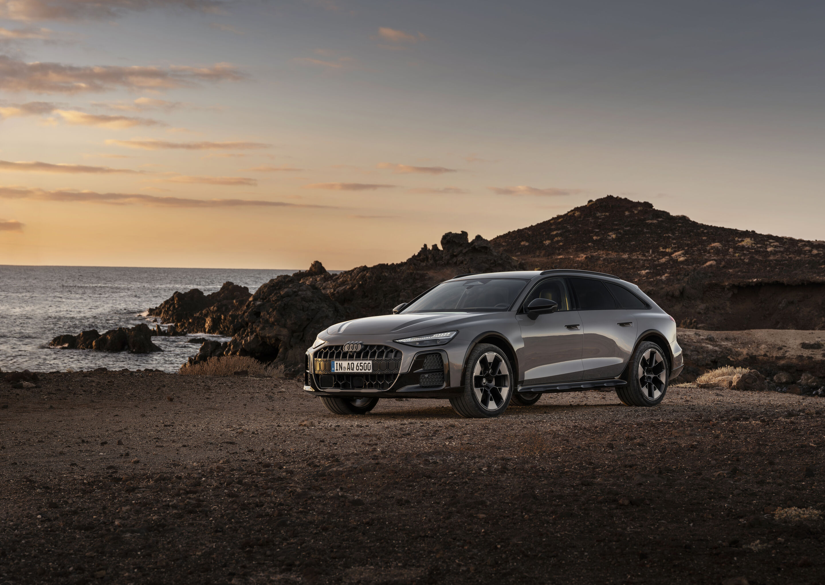 Audi A6 allroad quattro - Audi A6 allroad (plateau grey metallic) in side view at a rugged coastal landscape during sunset.