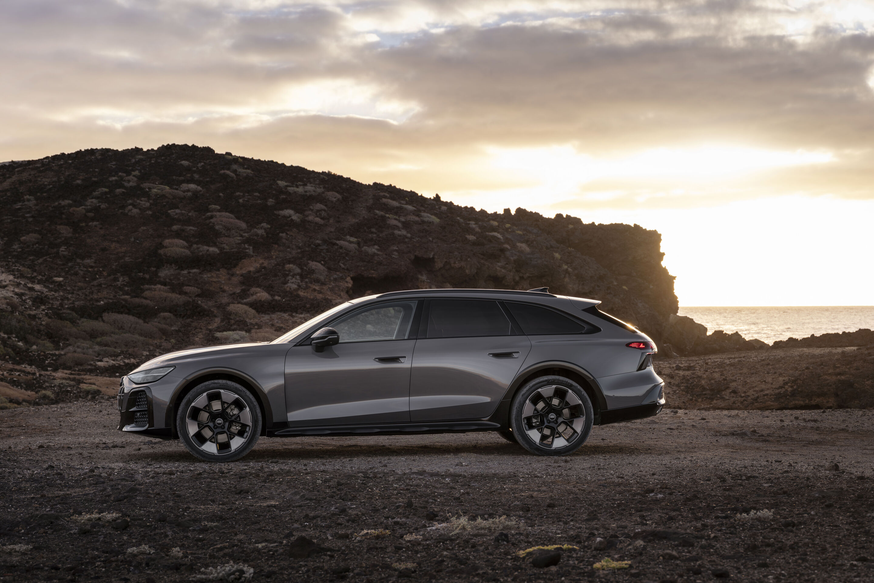 Audi A6 allroad quattro - Side silhouette of the Audi A6 allroad (plateau grey metallic) at low sun along a rugged coastline.
