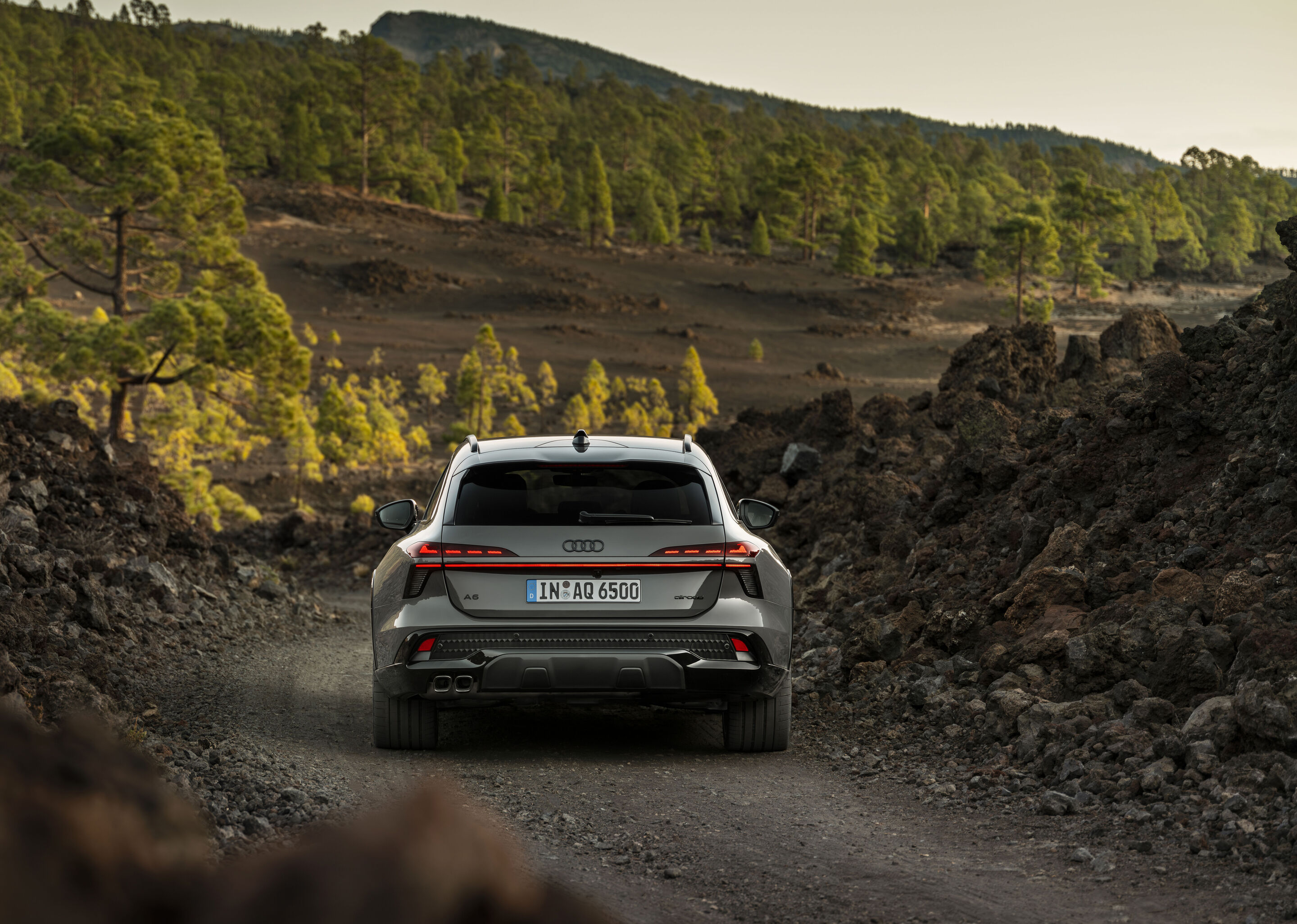 Audi A6 allroad quattro - Rear view of the Audi A6 allroad (plateau grey metallic) on a narrow gravel track in volcanic terrain.