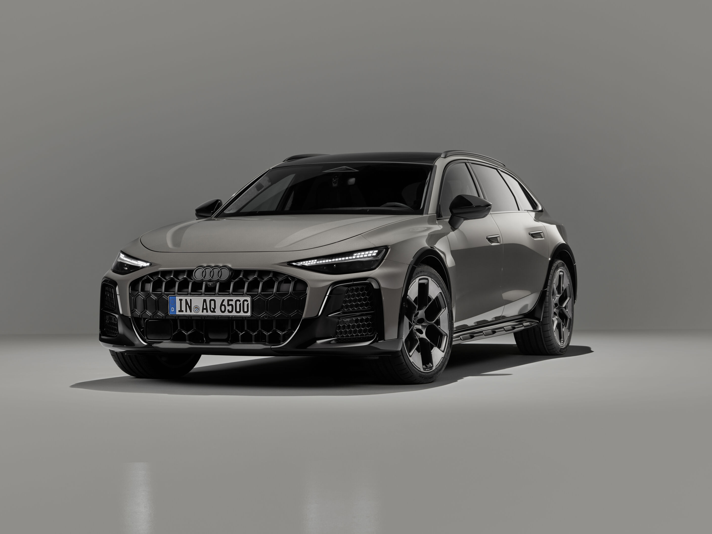 Audi A6 allroad quattro - Audi A6 allroad (plateaugrau metallic) in Dreiviertel-Frontansicht: Die Gitter des Singleframes und der großen seitlichen Lufteinlässe tragen vertikale Design-Elemente in Hexagon-Form und betonen die erhöhte Bodenfreiheit.