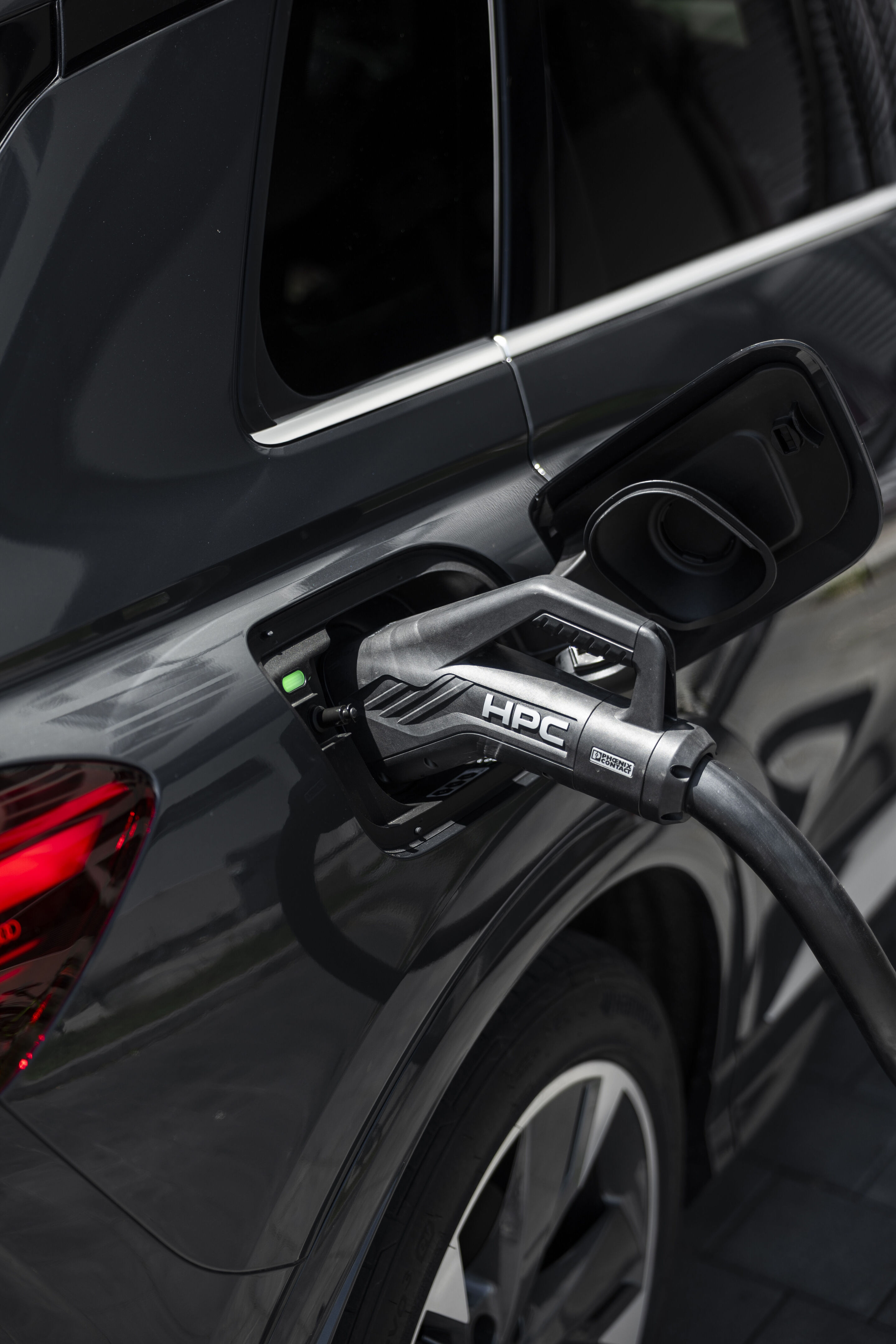 The right car for any situation: the Audi Q4 e-tron takes to the streets - Audi Q4 SUV e-tron in Tambora grey, outdoor static shot, exterior, detail while charging at an HPC fast-charging station.