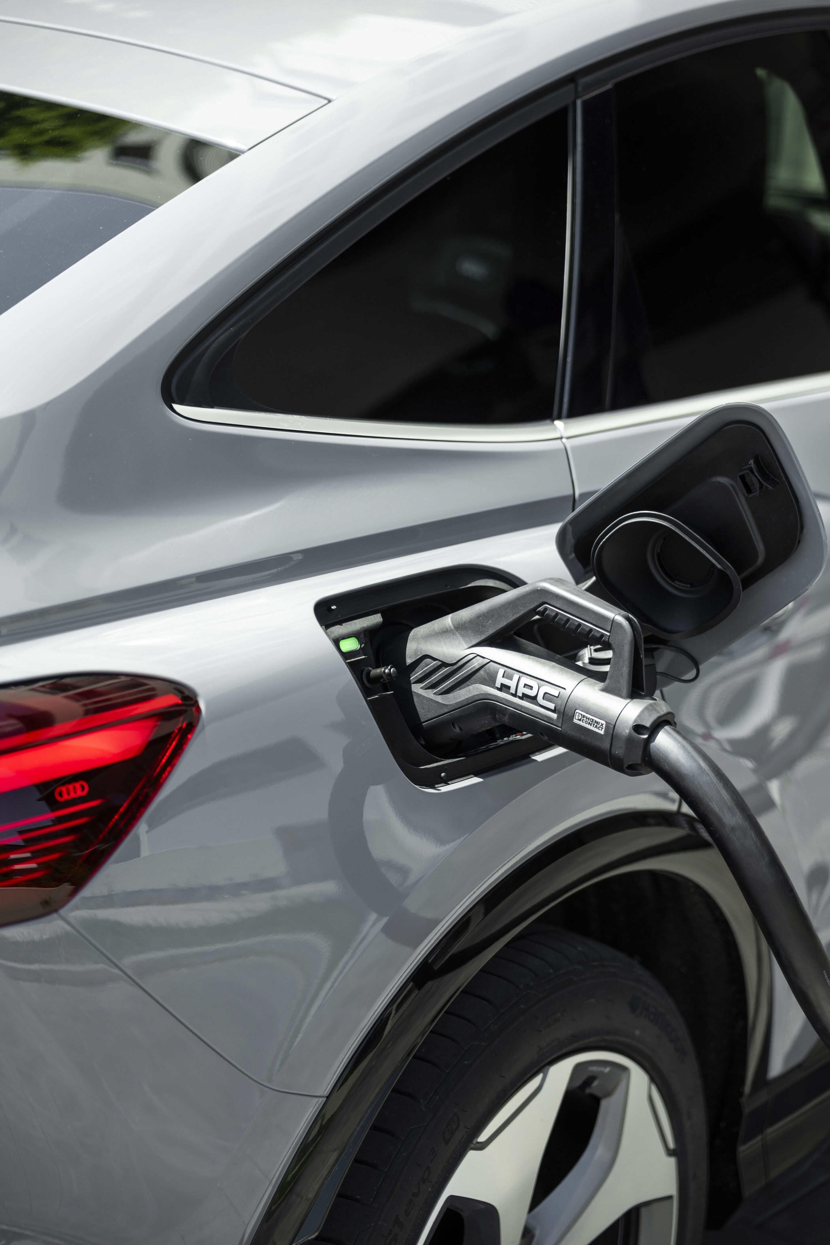 The right car for any situation: the Audi Q4 e-tron takes to the streets - Audi Q4 Sportback e-tron in Pebble grey, outdoor static shot, exterior, detail while charging at an HPC fast-charging station.
