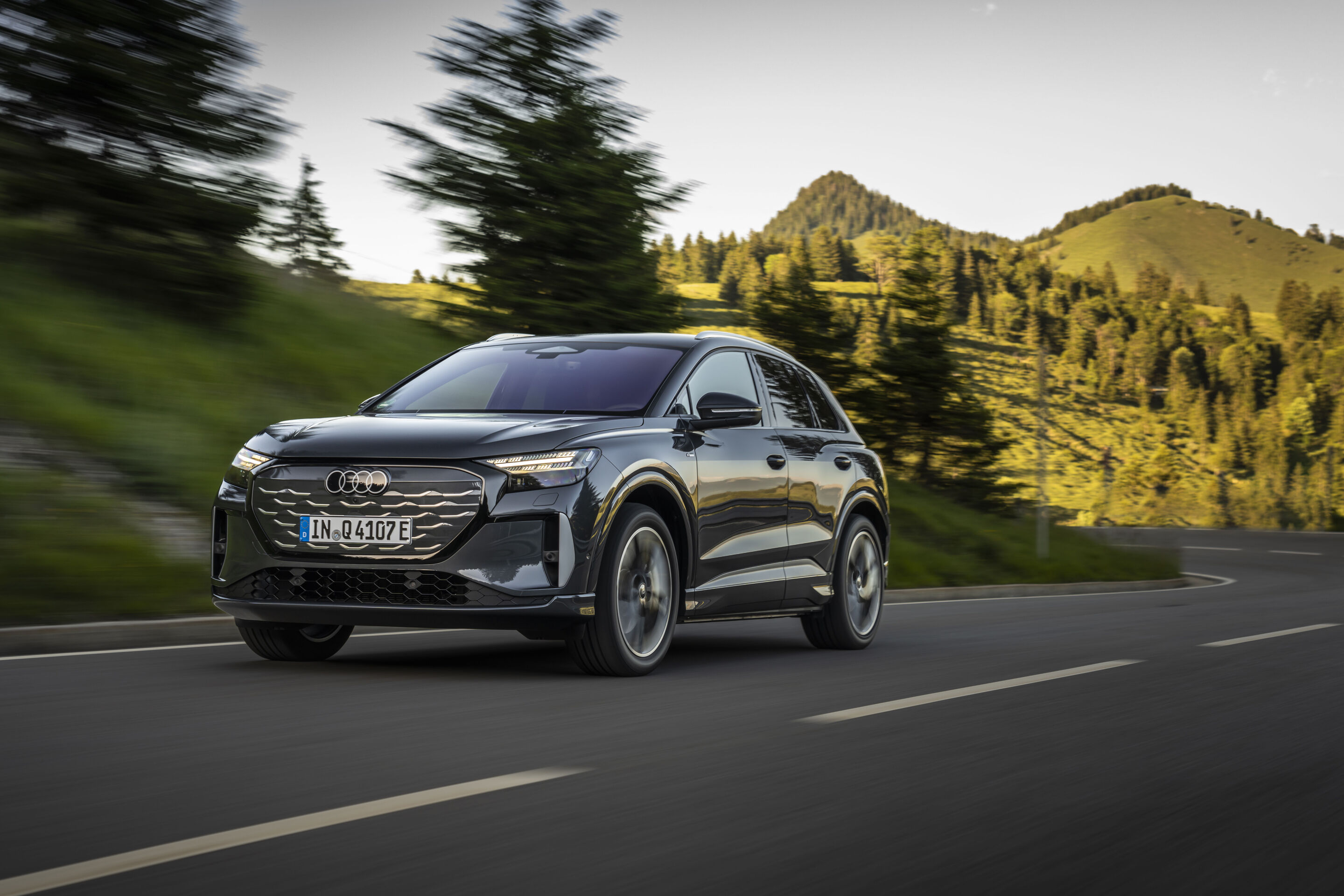 Ein Auto für jeden Moment: Unterwegs im Audi Q4 e-tron - Audi Q4 SUV e-tron in Tamboragrau, Outdoor-Fahraufnahme, Exterieur, Dreiviertelfrontansicht auf kurvenreicher Straße in alpiner Landschaft.