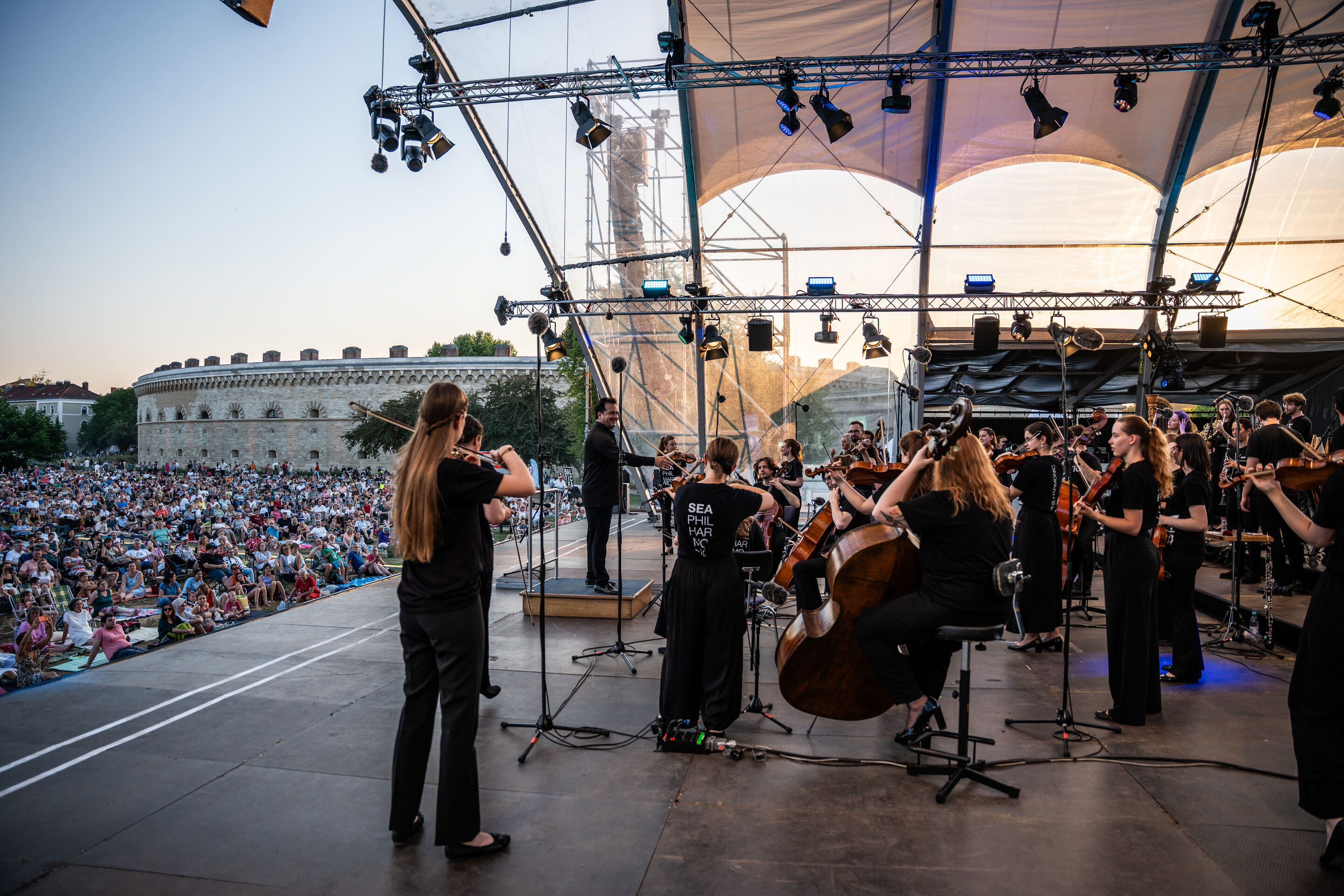 Baltic Sea Philharmonic performing at the classical open-air concert in Klenzepark - View from the stage of the 2026 Classical Open-Air Concert in Klenzepark towards the Baltic Sea Philharmonic and conductor Robert Treviño, as well as the audience in...